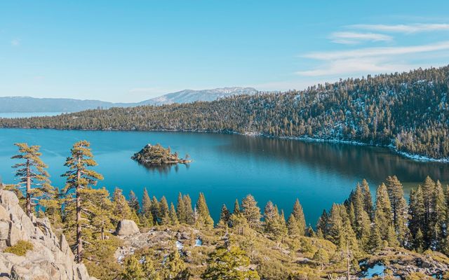 blue lake surrounded by green trees under blue sky during daytime