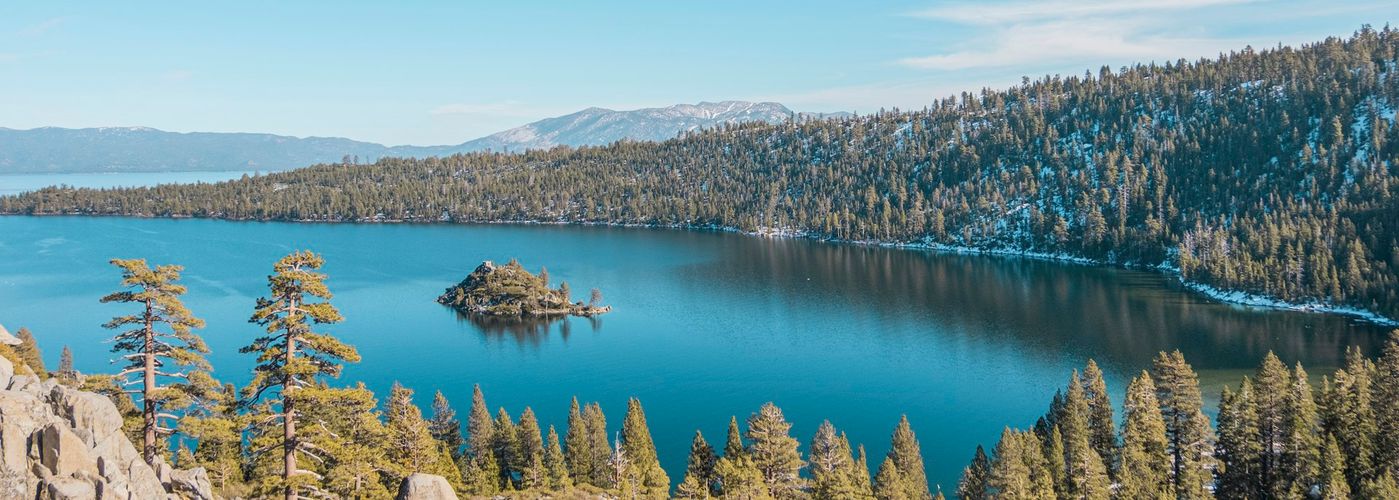 blue lake surrounded by green trees under blue sky during daytime