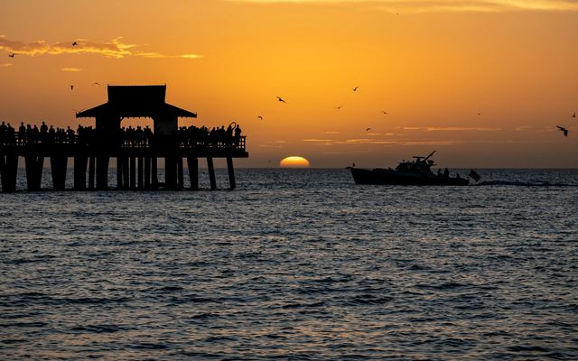 a boat in the water near a pier at sunset