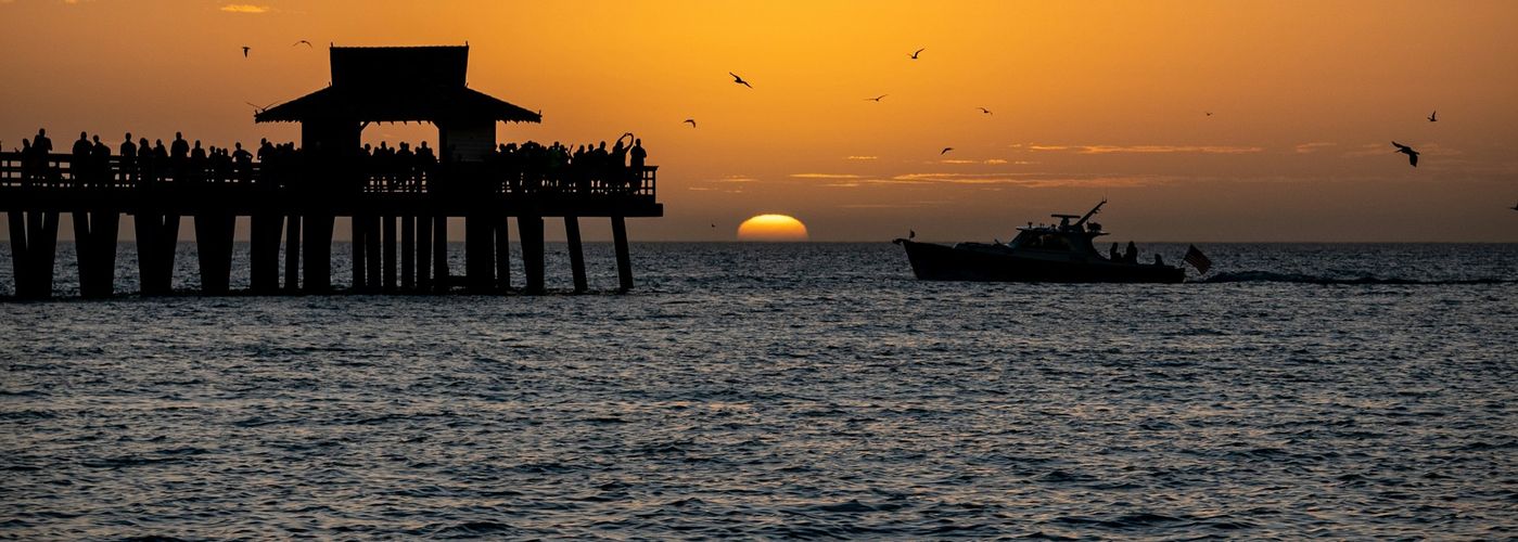 a boat in the water near a pier at sunset