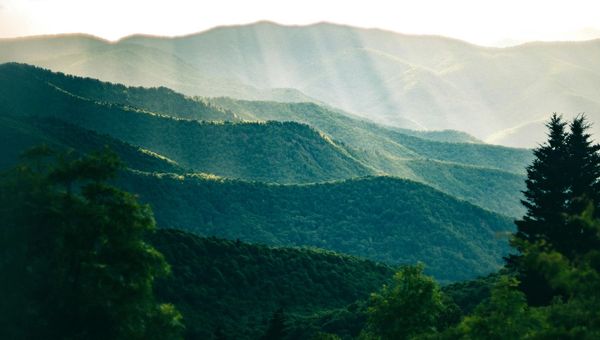 the sun shines through the clouds in the mountains