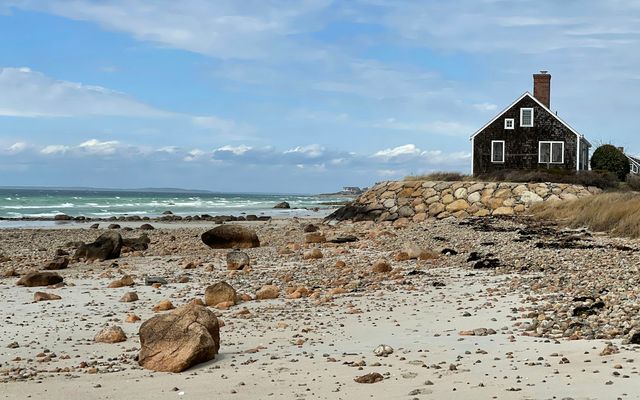 a house sitting on top of a sandy beach next to the ocean