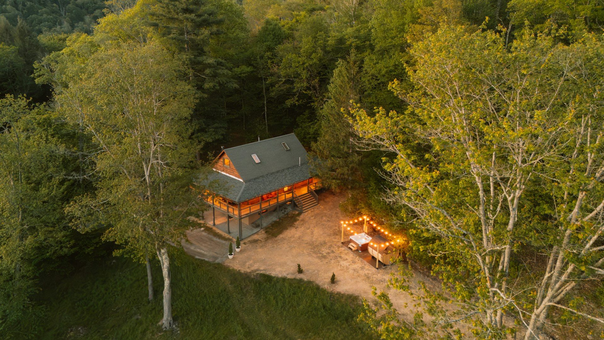 Forest cabin with an illuminated outdoor dining area at dusk