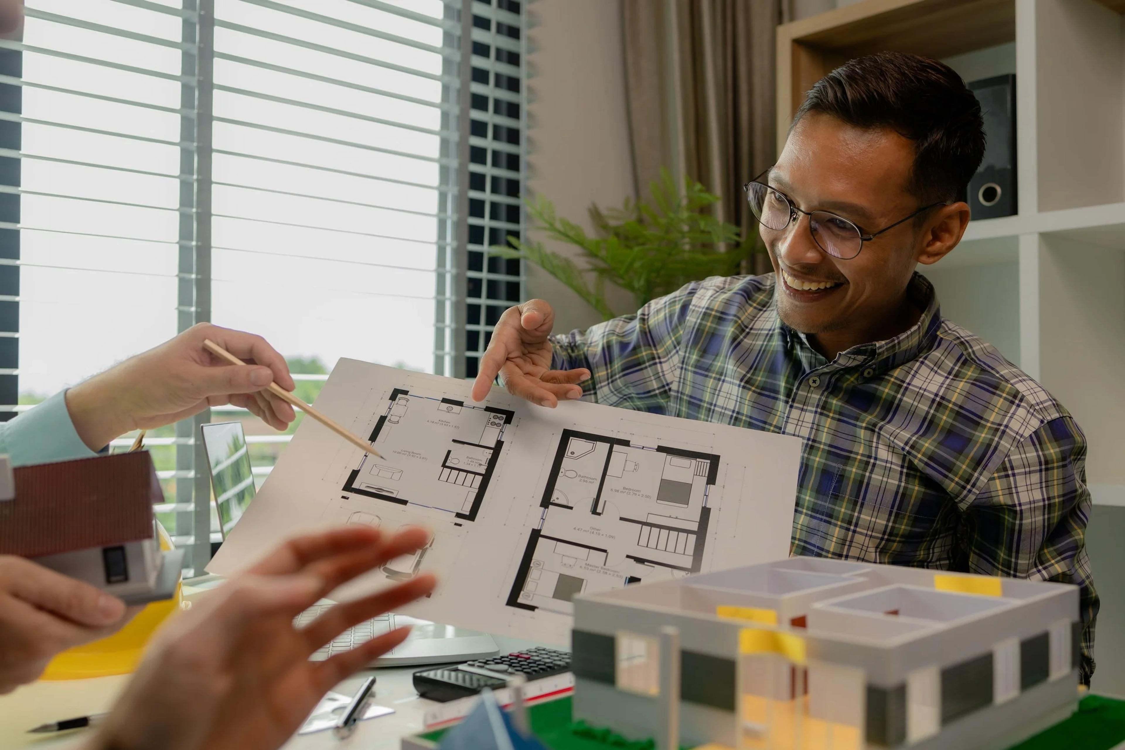 Man reviewing renovation floor plans and a model home with his interior designer