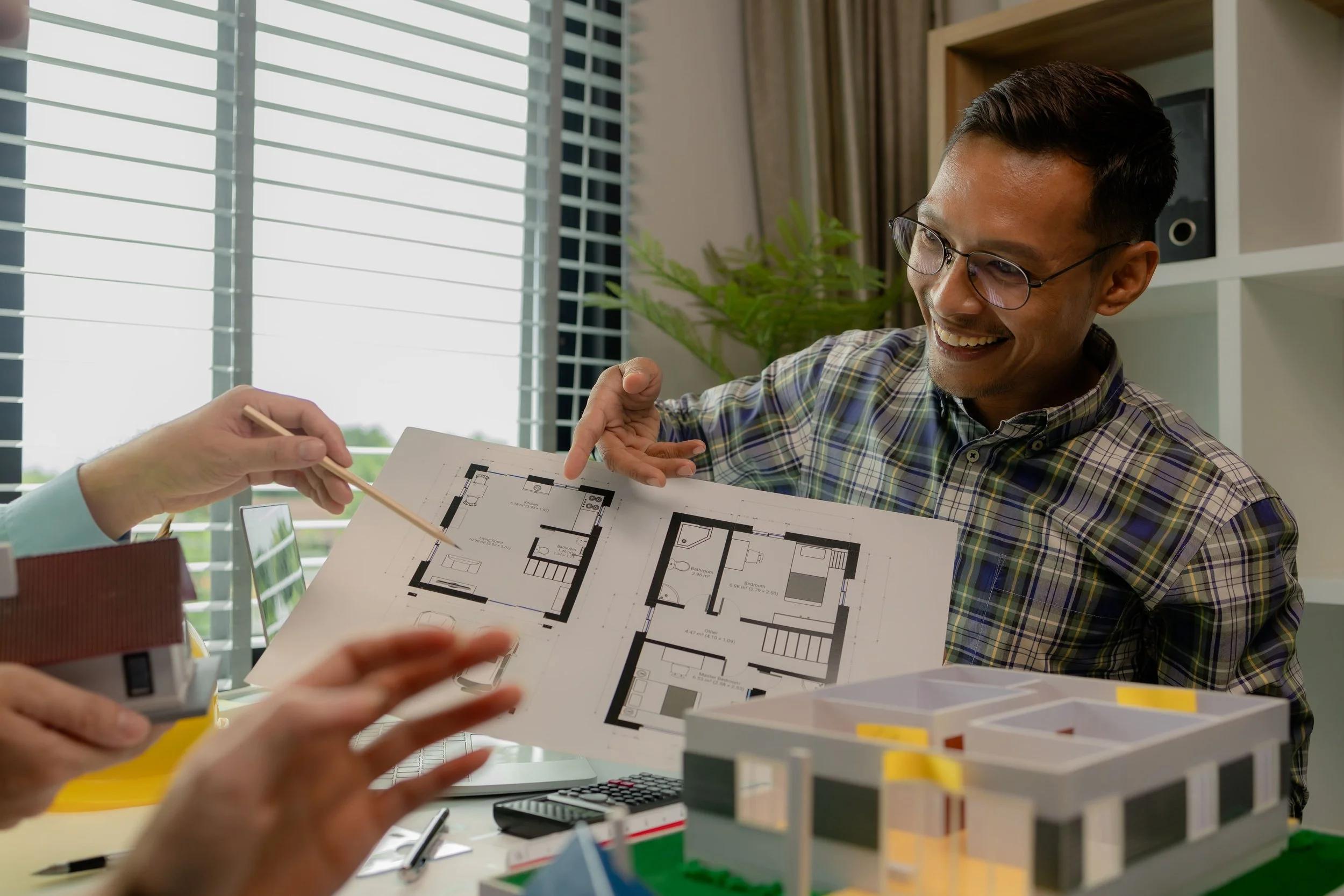 Man reviewing renovation floor plans and a model home with his interior designer