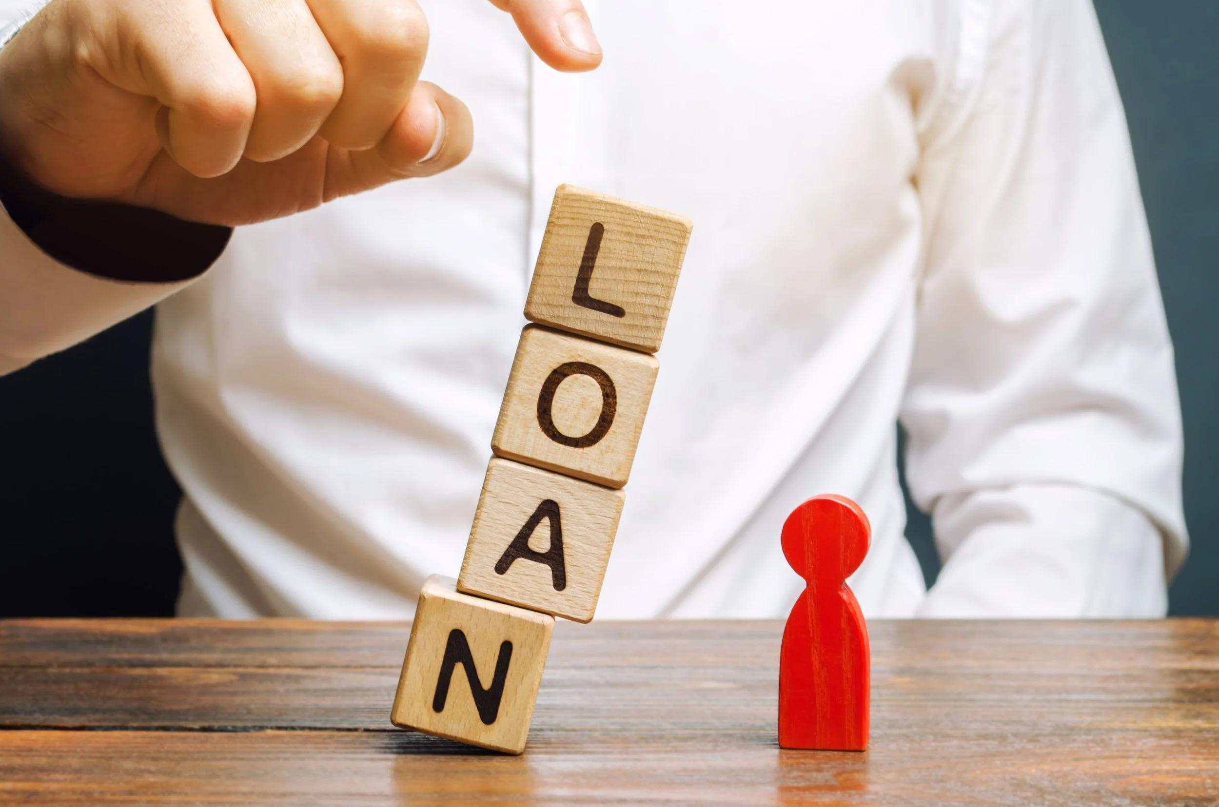 Wooden blocks spelling LOAN beside a red figure: the risk of overborrowing for property