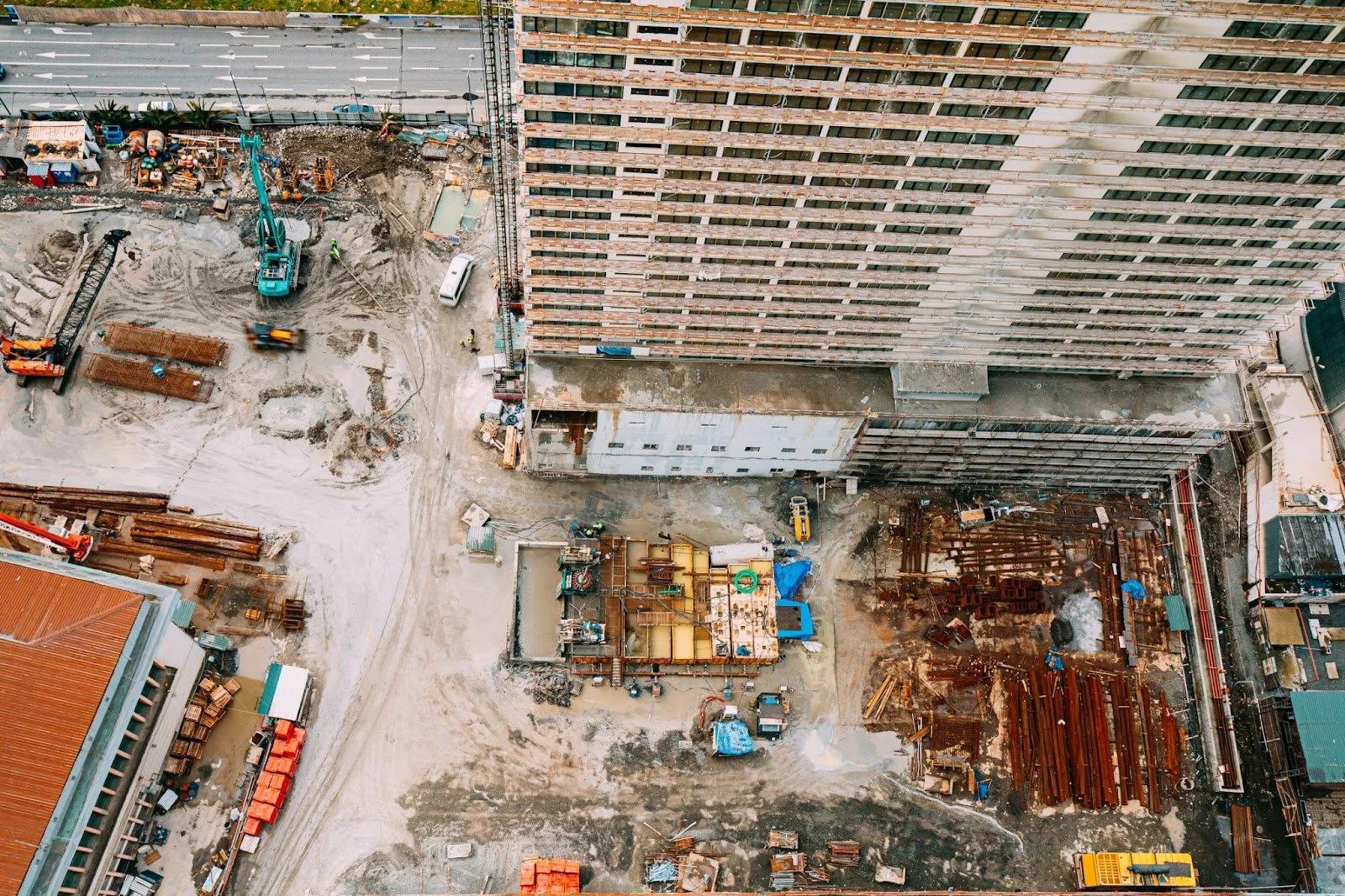 Aerial view of a new HDB construction site with cranes and foundations