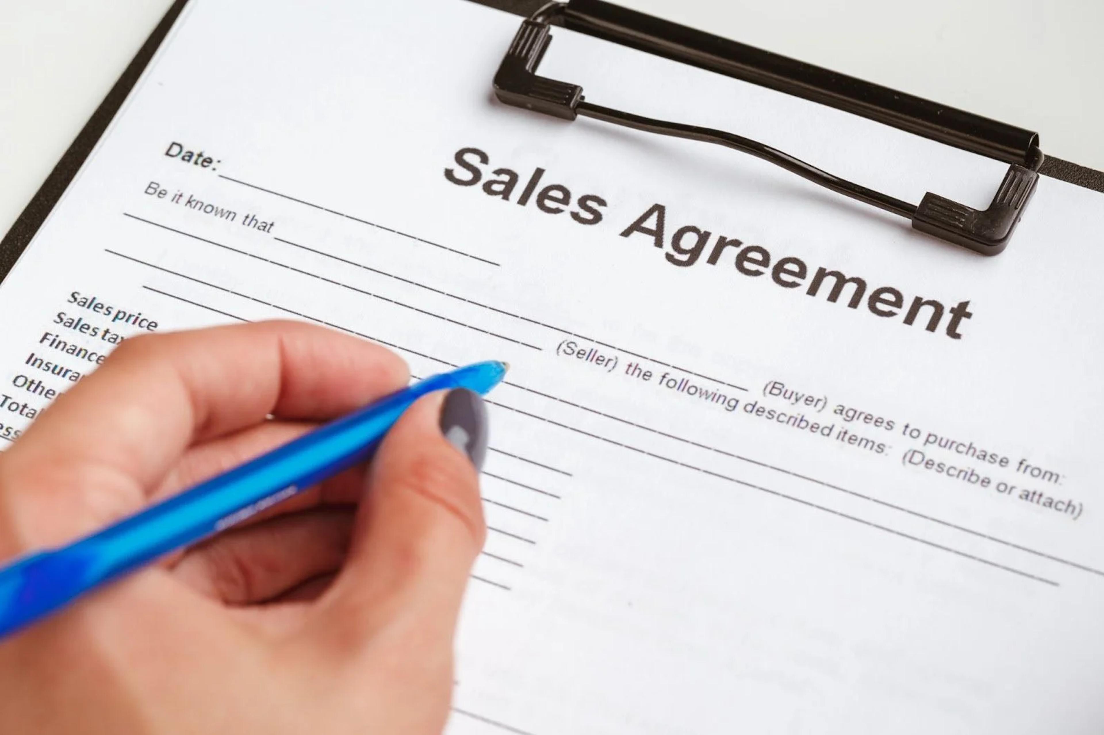Signing a property sales agreement with a blue pen