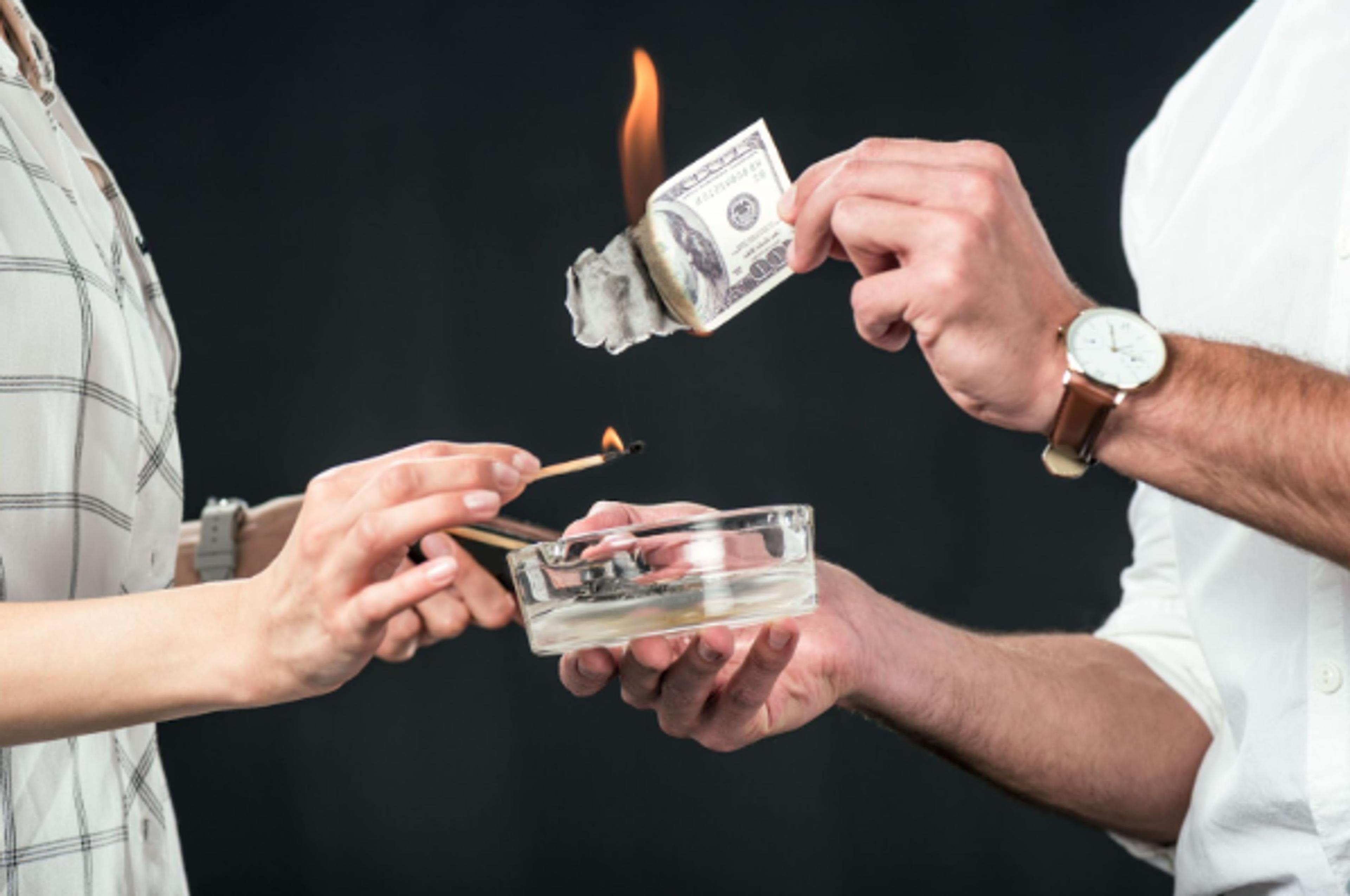 Couple burning banknotes: money wasted on the wrong condo purchase