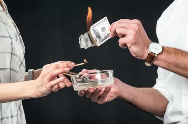 Couple burning banknotes: money wasted on the wrong condo purchase