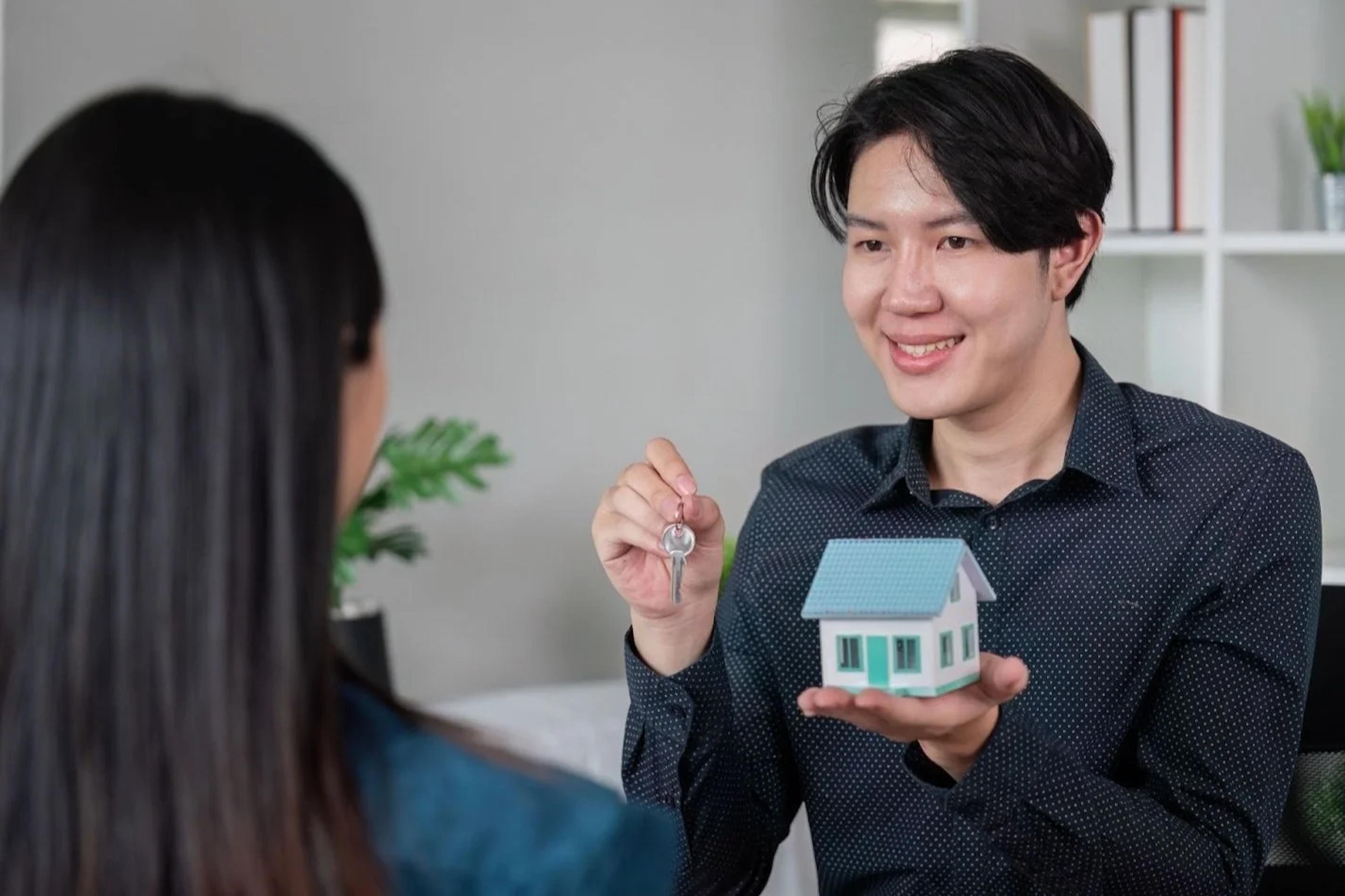 Seller handing house keys and a model home to the buyer
