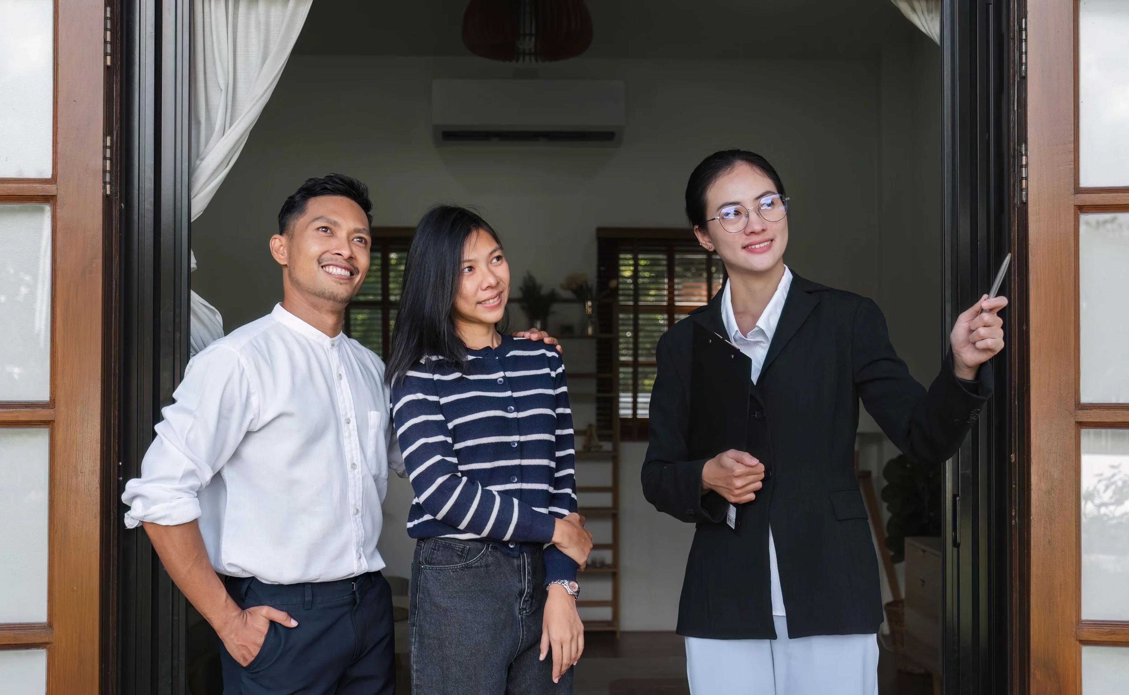 Property agent showing a young Asian couple around a home