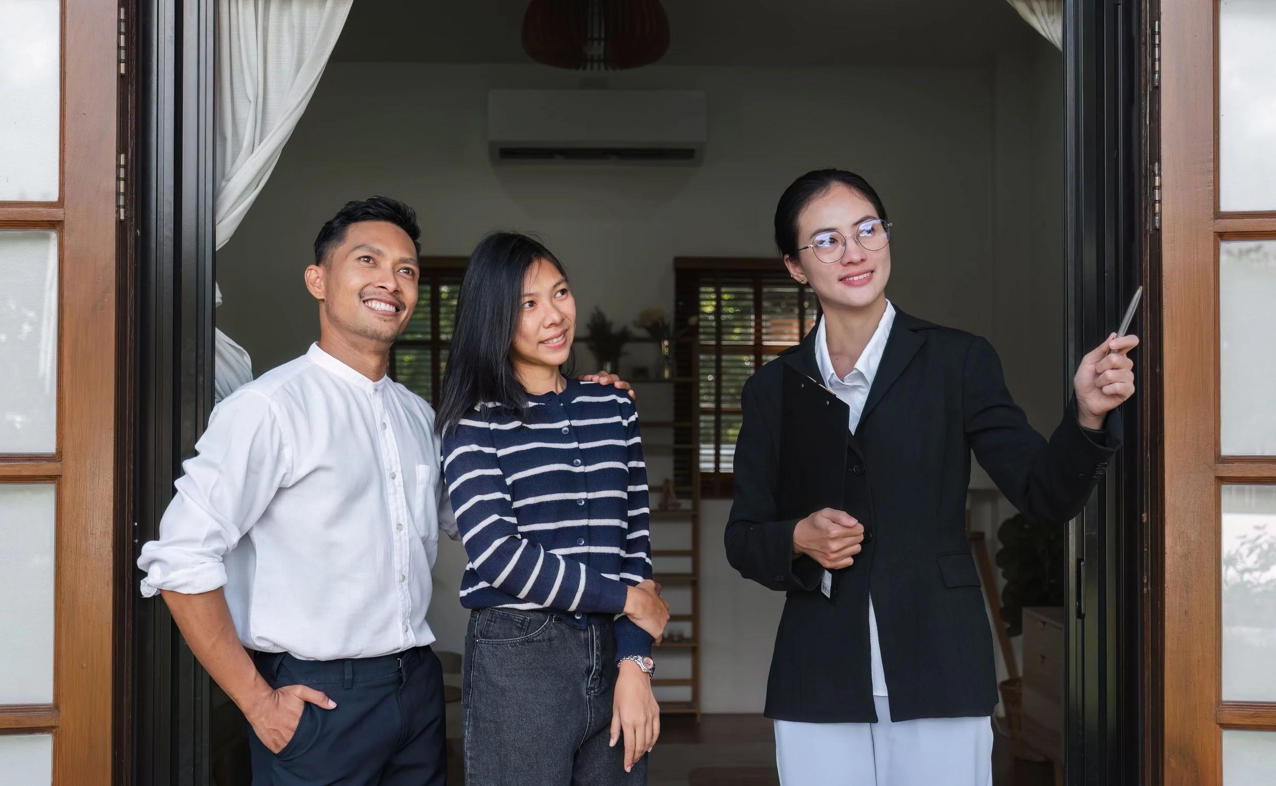Property agent showing a young Asian couple around a home