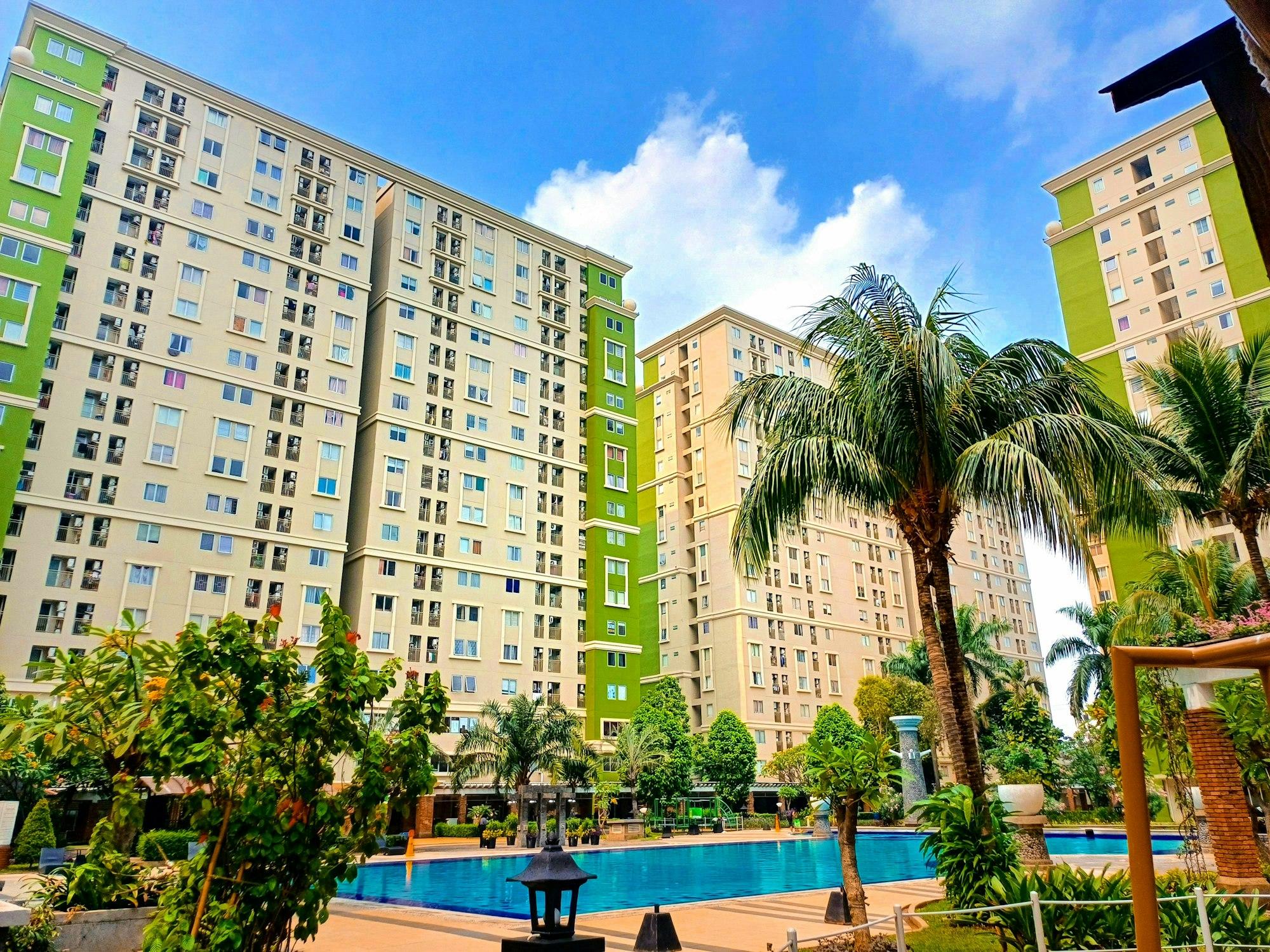 被棕榈树和住宅大楼环绕的公寓游泳池