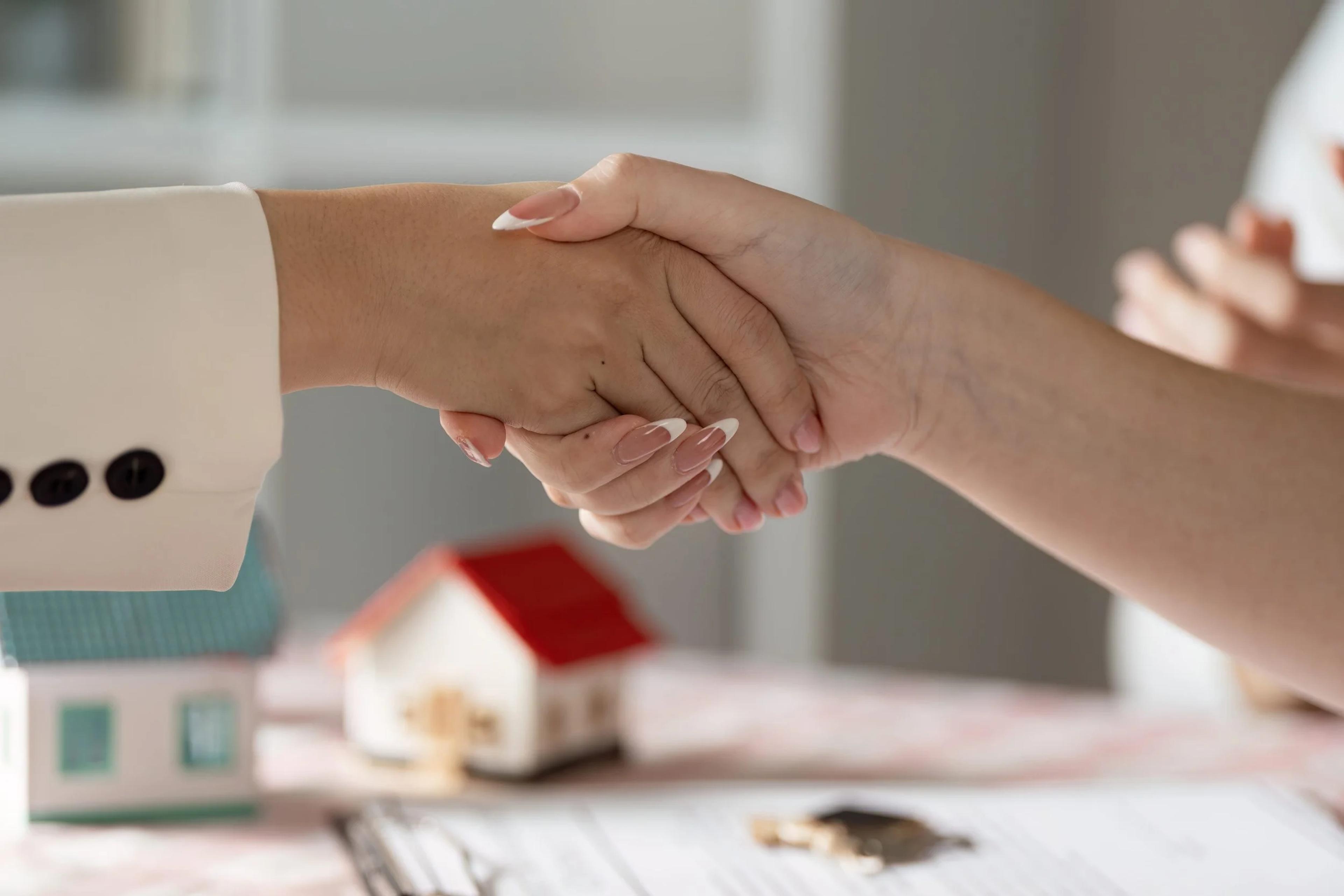 Handshake over model houses to close a property purchase