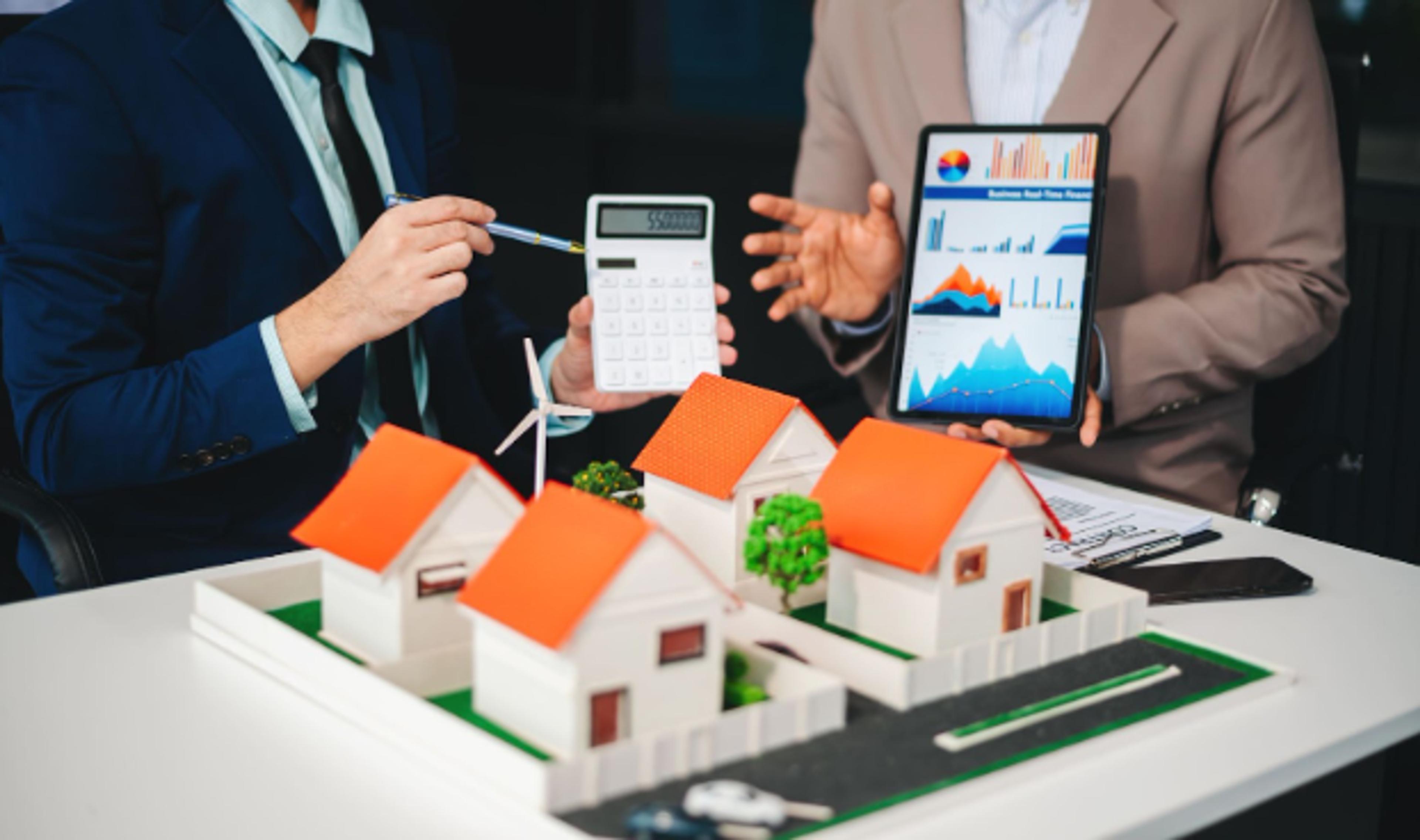 Advisers reviewing a housing development model with a calculator and investment charts