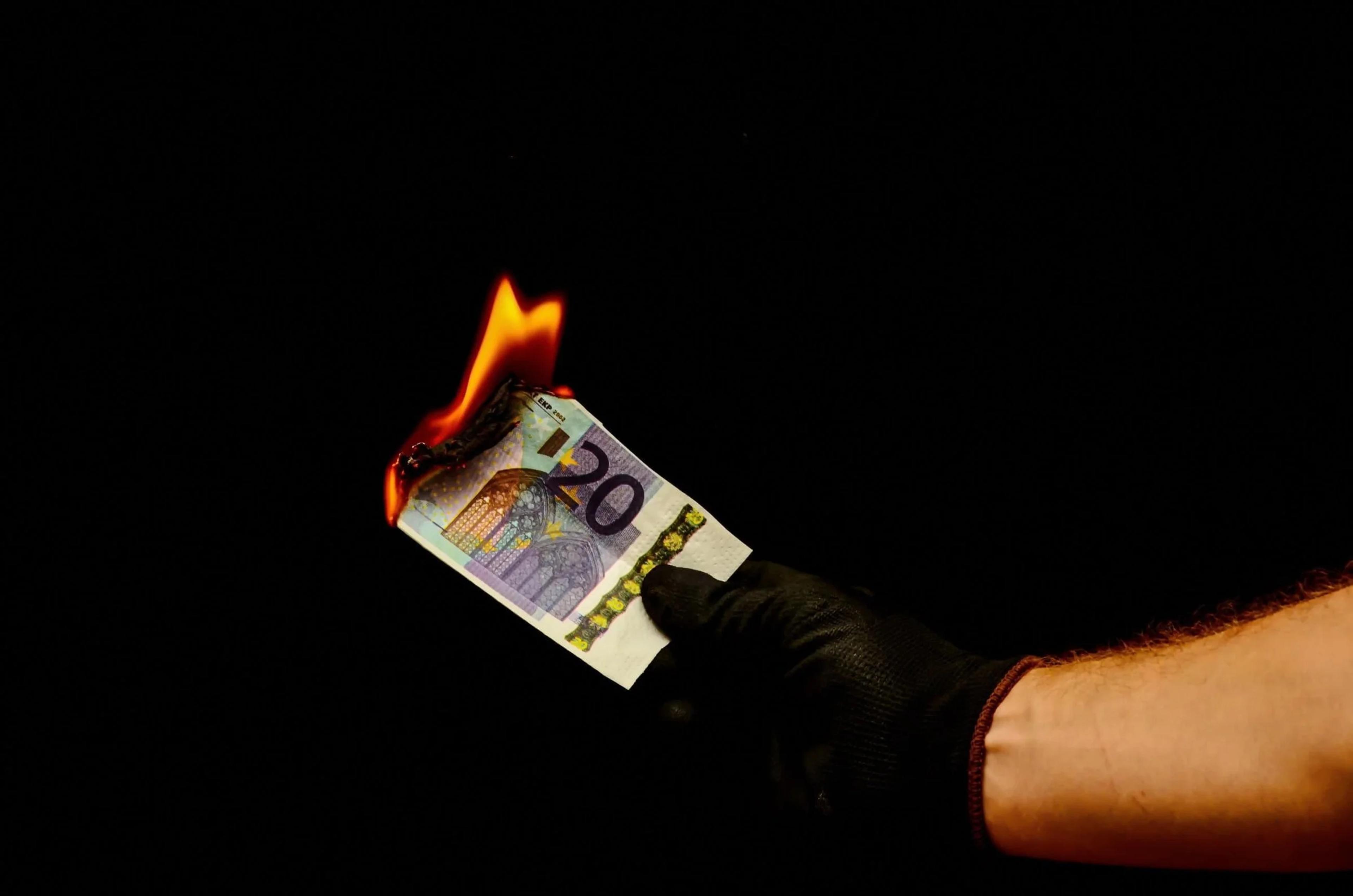 Banknote burning in a hand: money lost to property investment mistakes