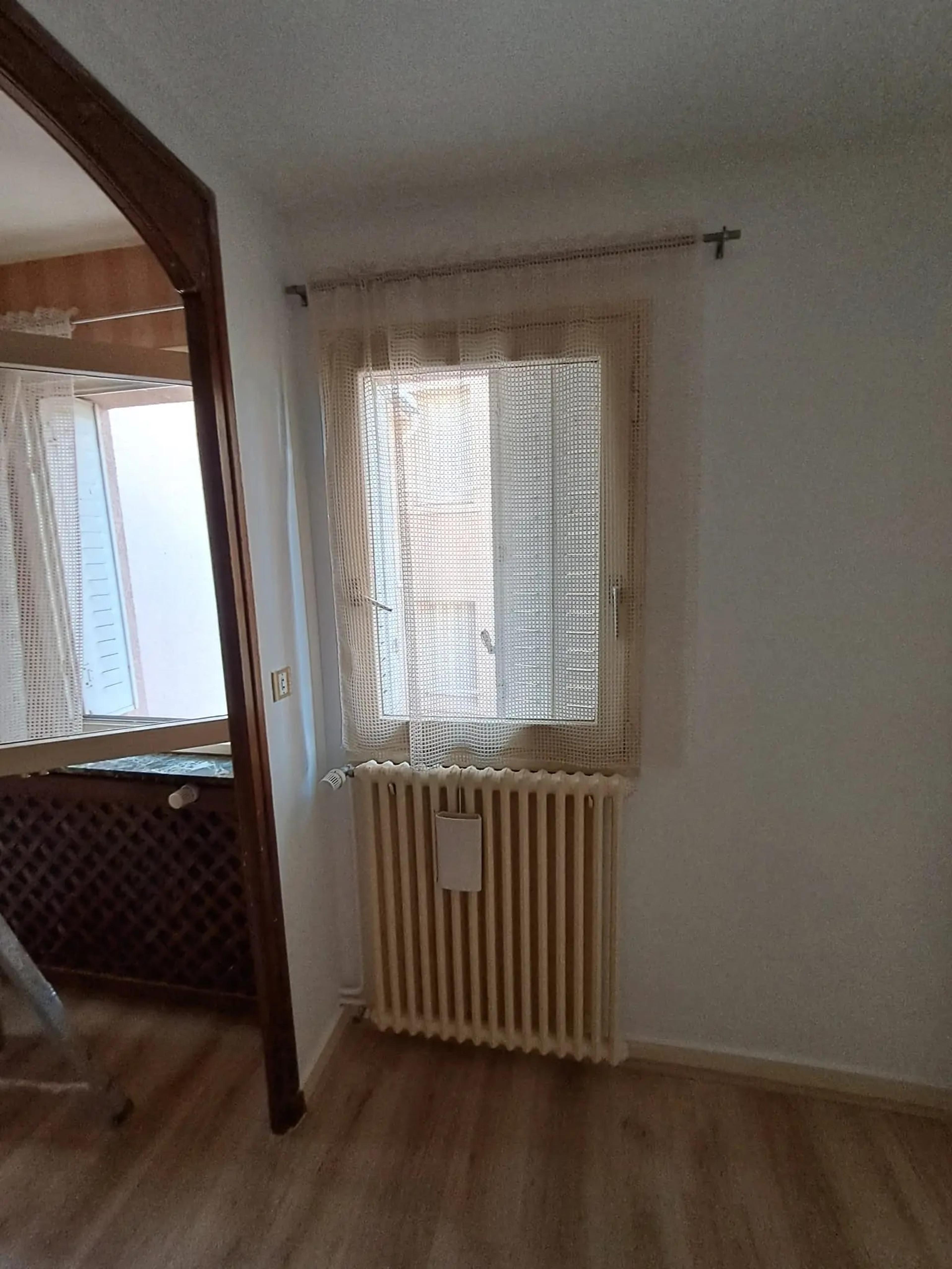 Fenêtre et radiateur après travaux, murs repeints en blanc