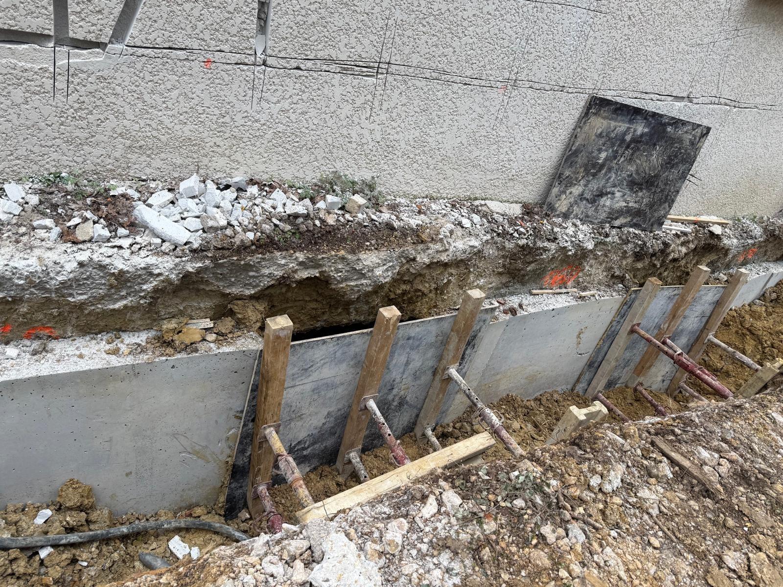 Fouille ouverte le long d’une maison, coffrage métallique étayé le long des fondations