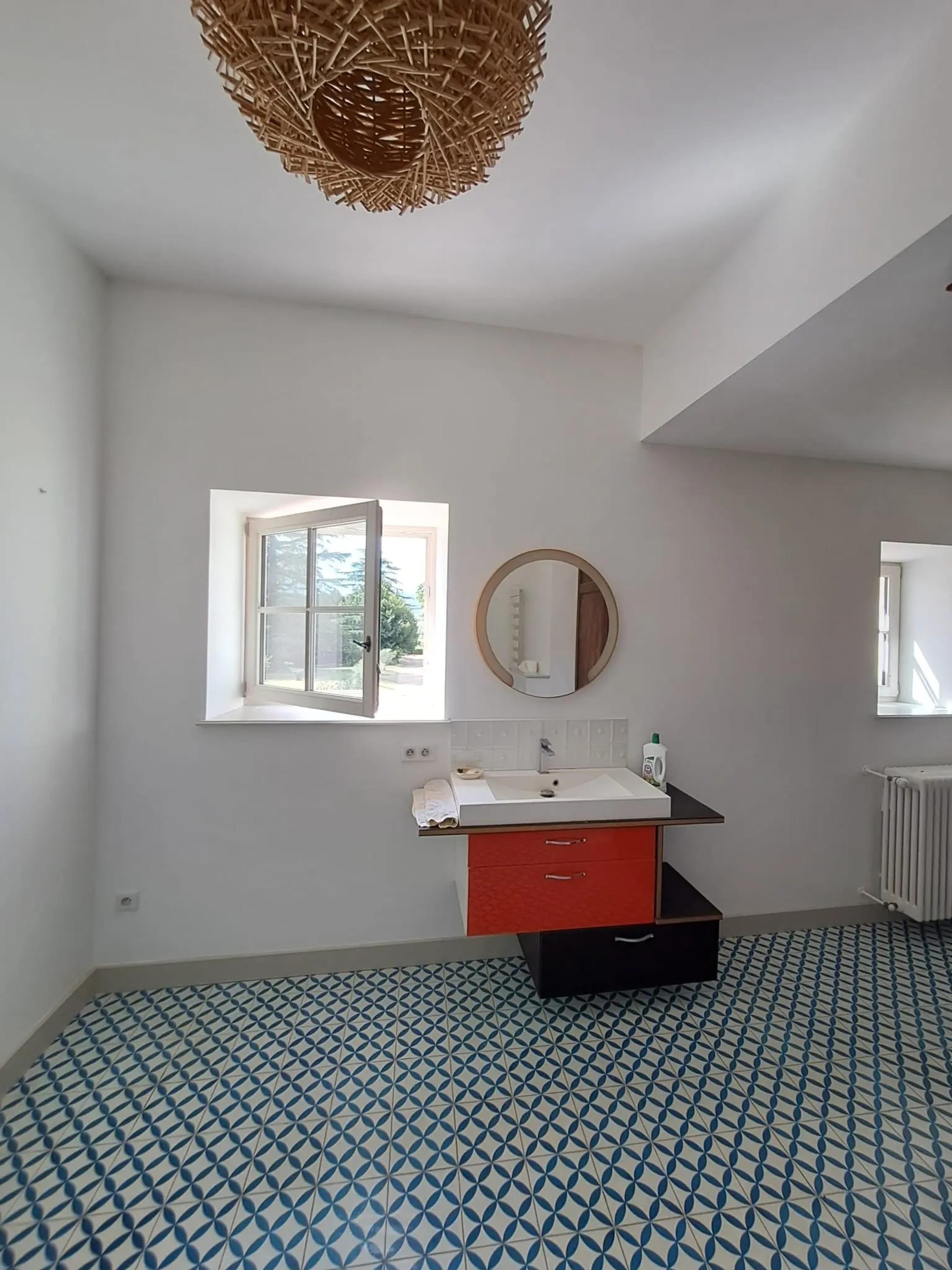 La salle de bains après travaux : vasque, miroir rond et fenêtre