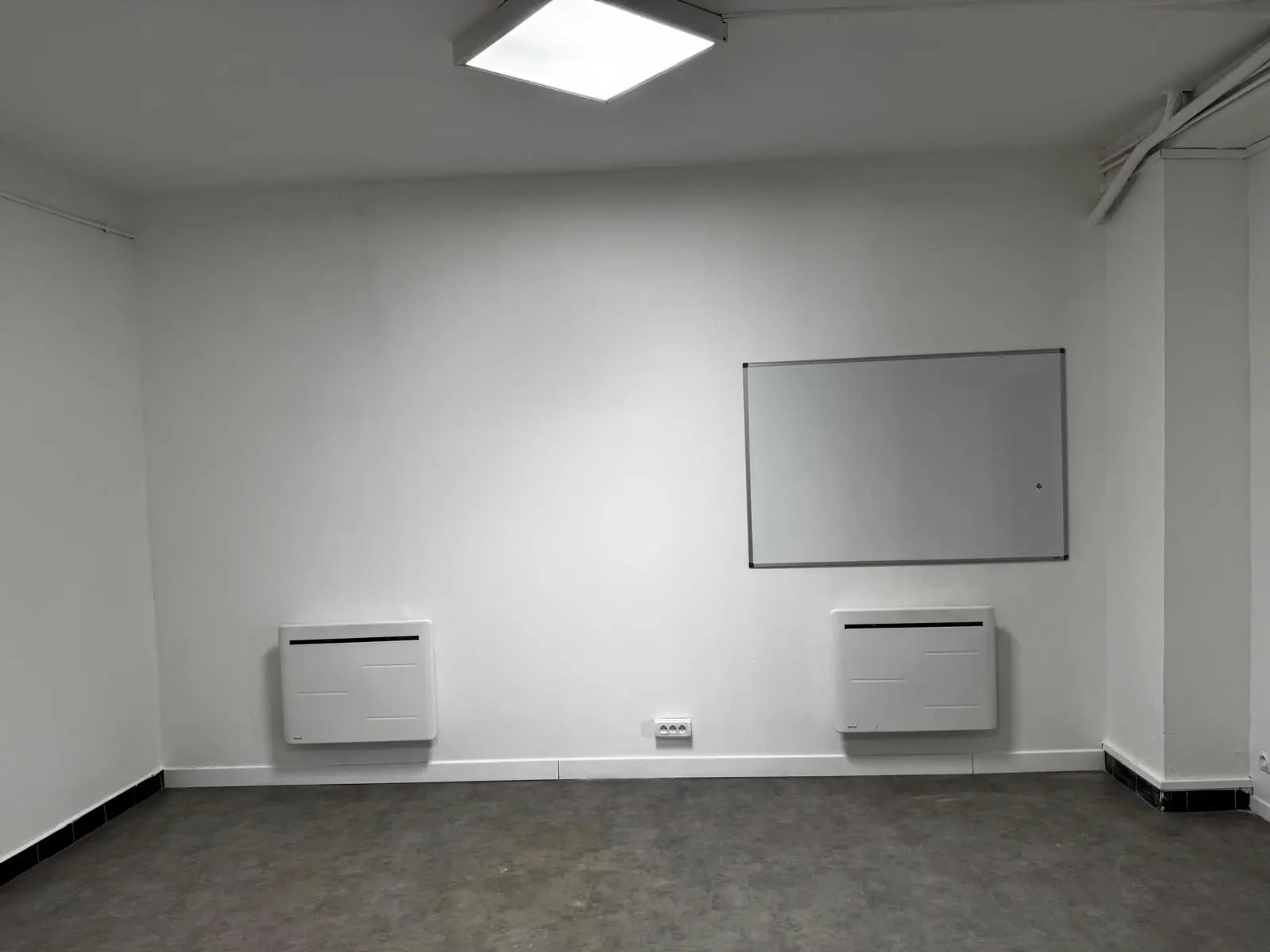 La même salle après travaux : murs et plafond repeints, tableau blanc et radiateurs