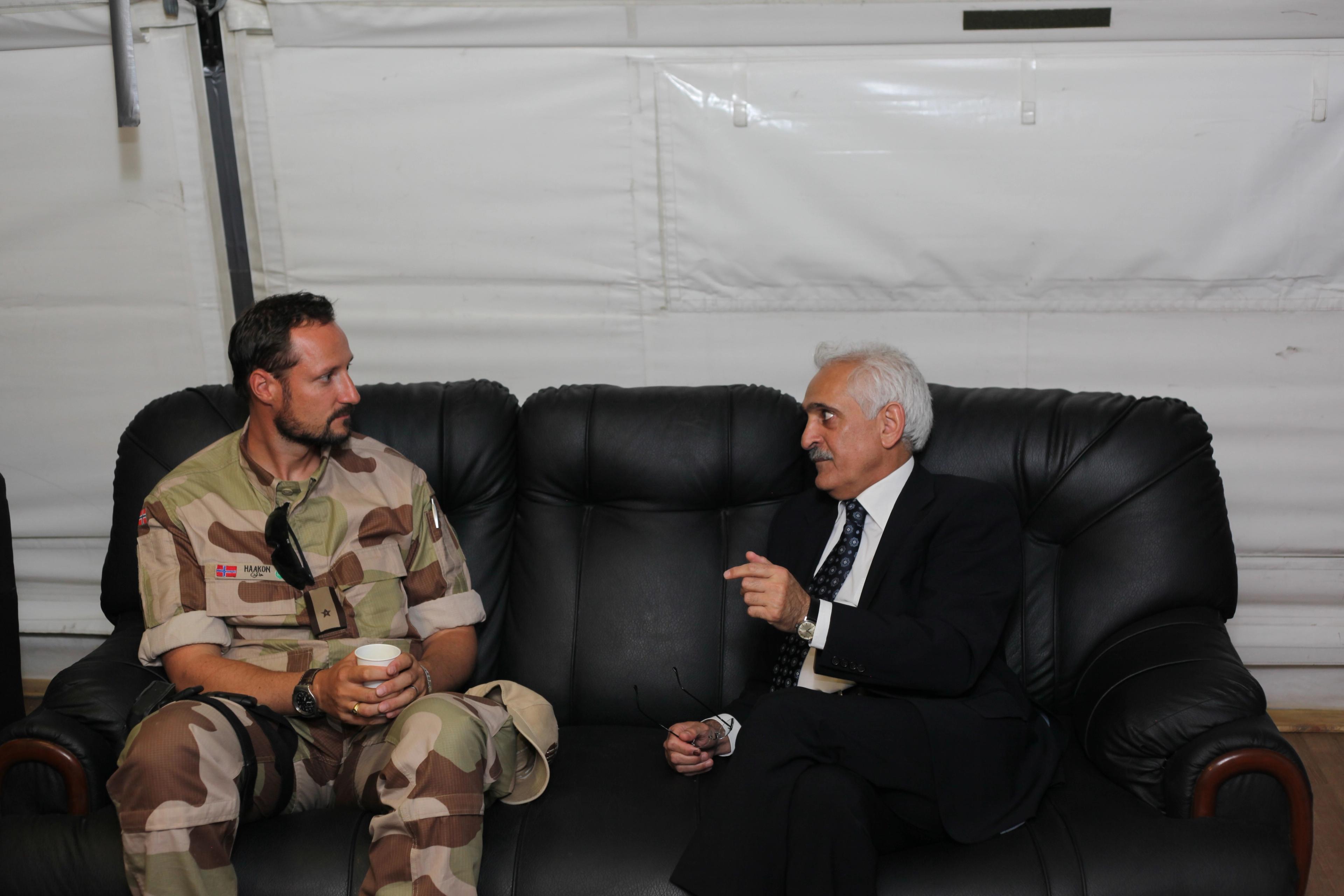 Kronprinsen i uniform sitter i en sort sofa og snakker med utenriksministeren.