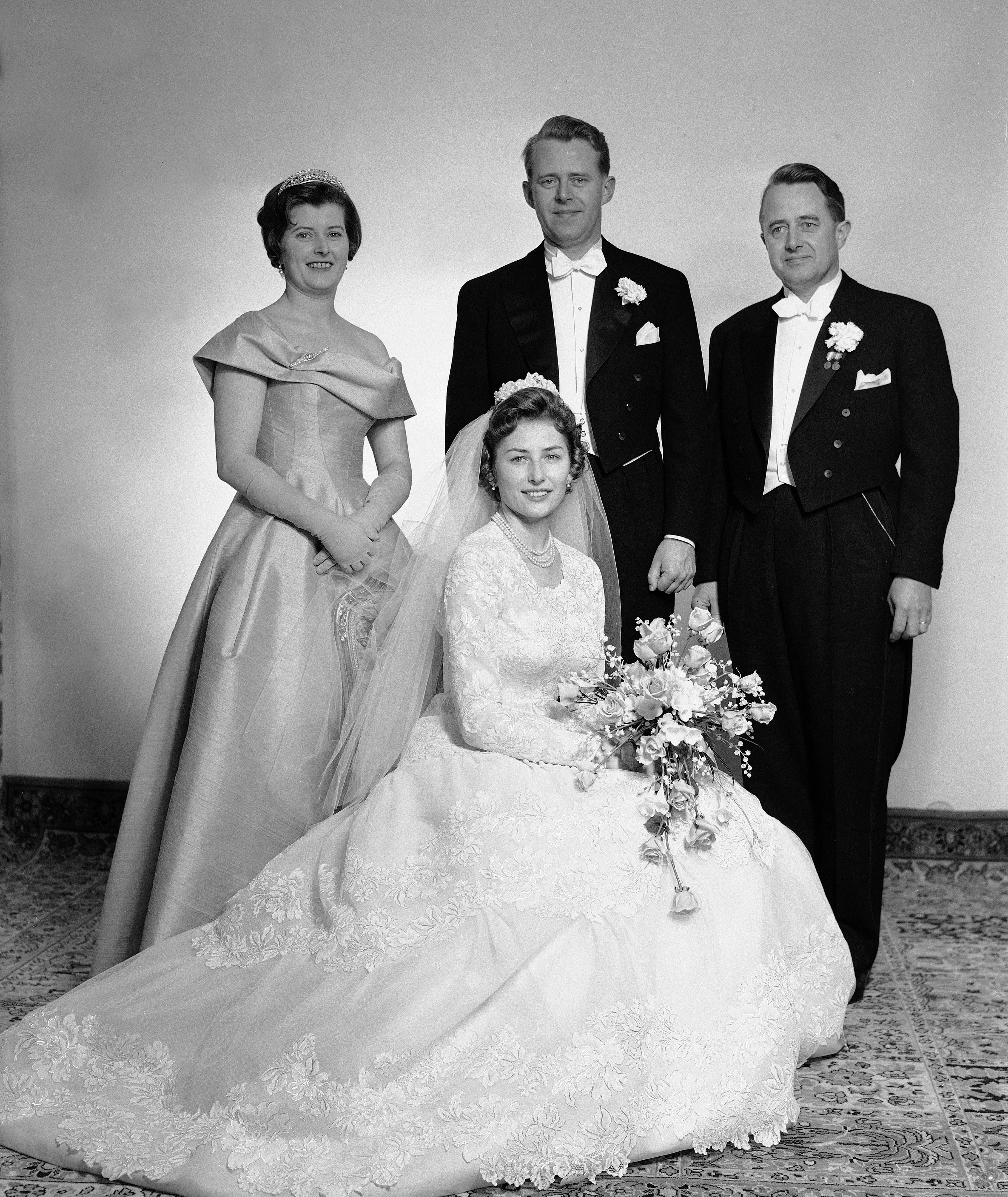 Prinsesse Astrid sitter foran, mens brudgommen står bak med en forlover på hver side.