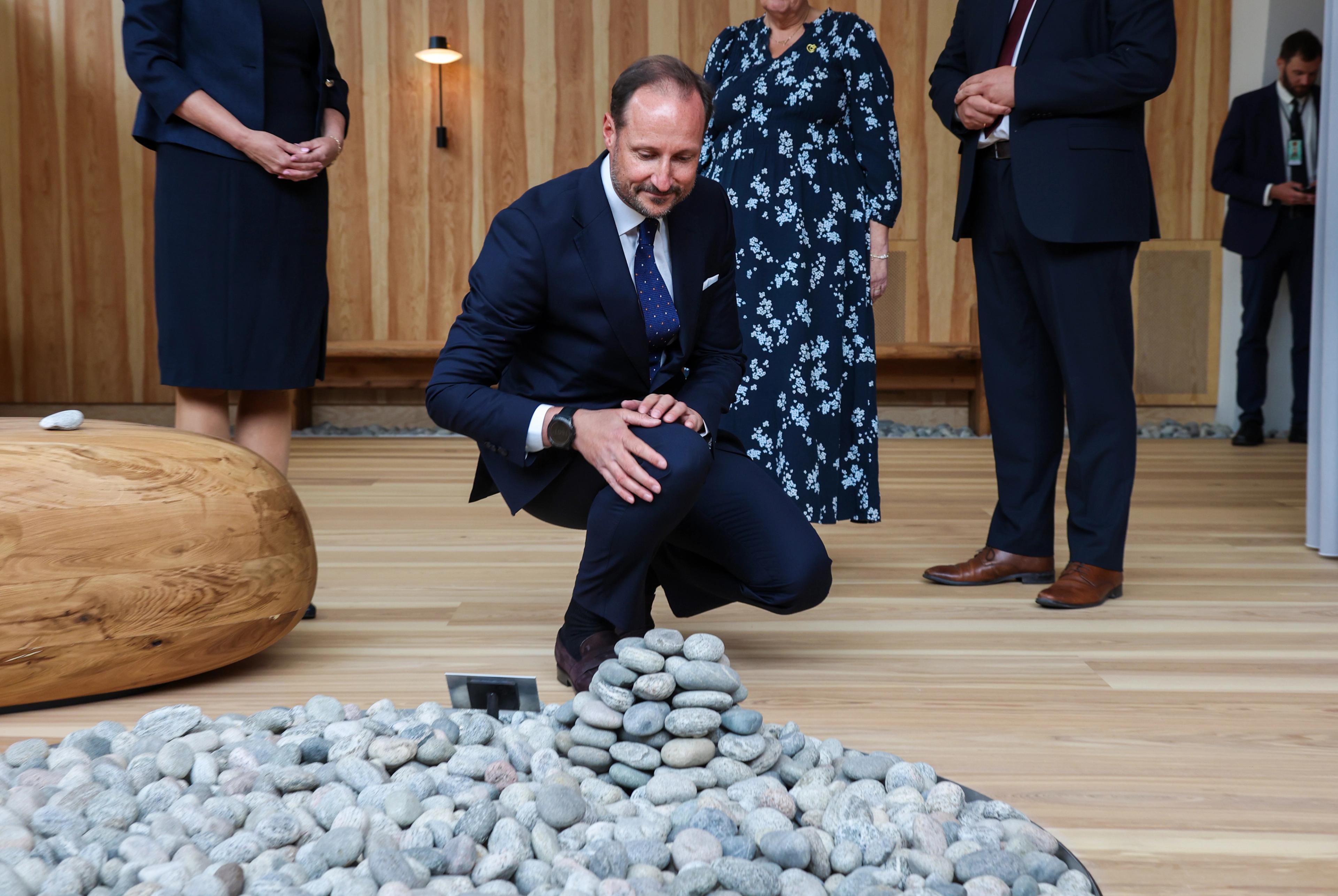 Kronprinsen på huk ved steinsirkelen der han nettopp har lagt en stein til varden.