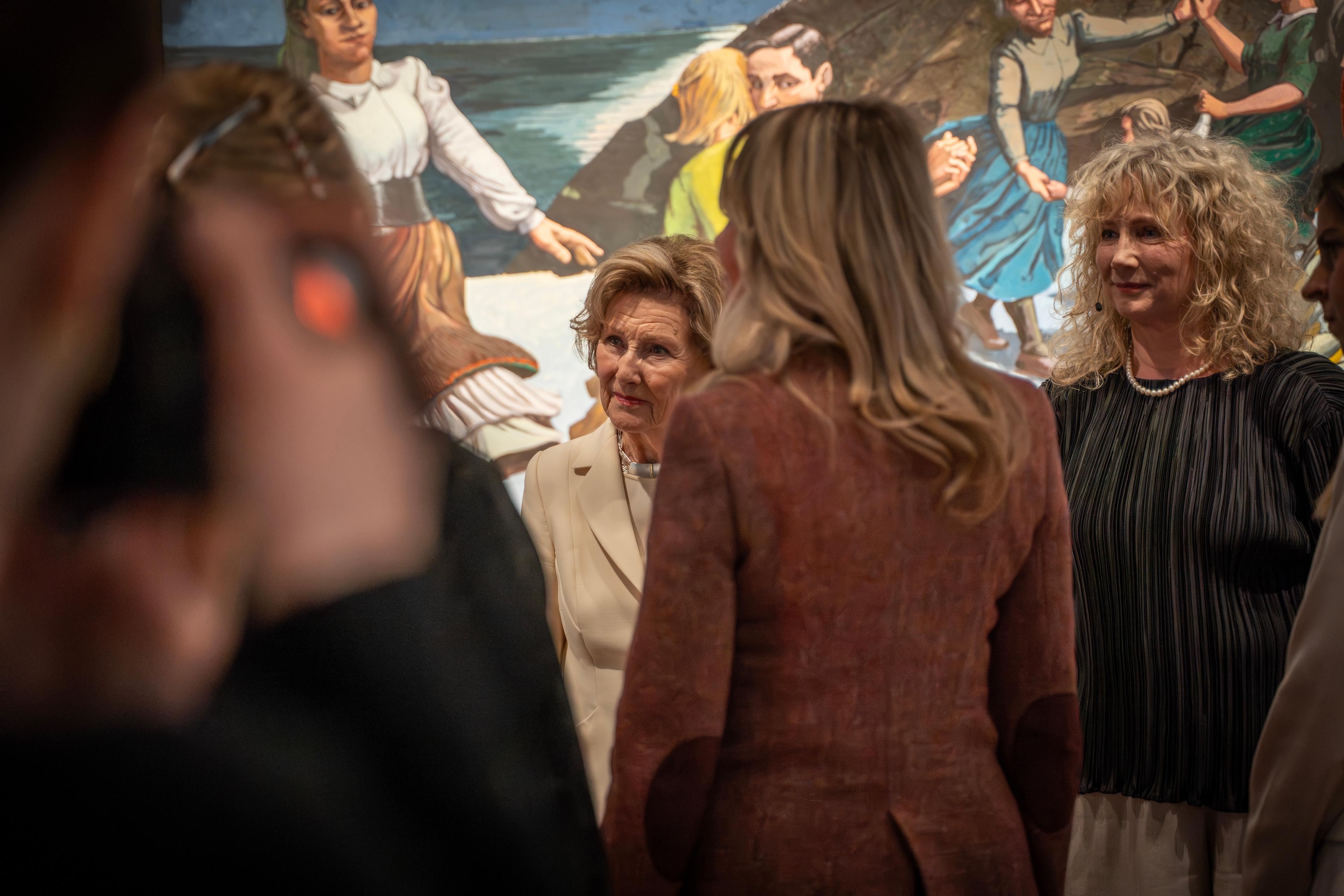 Dronning Sonja samtaler i ring med flere personer. Regos verk "Dansen" syns i bakgrunnen.