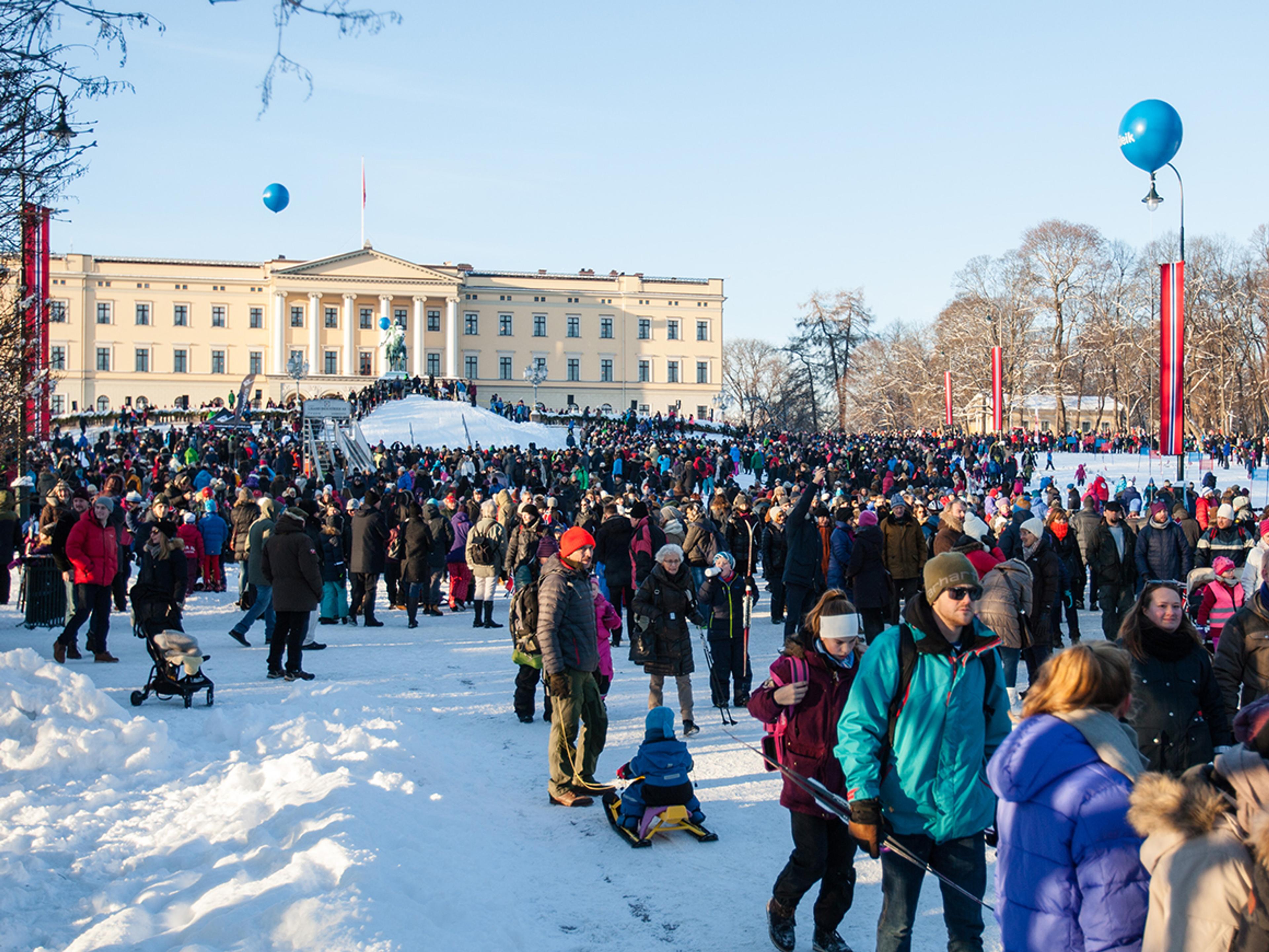 En snødekket slottsplass full av mennesker, mange i skiutstyr. Slottet i bakgrunnen. 