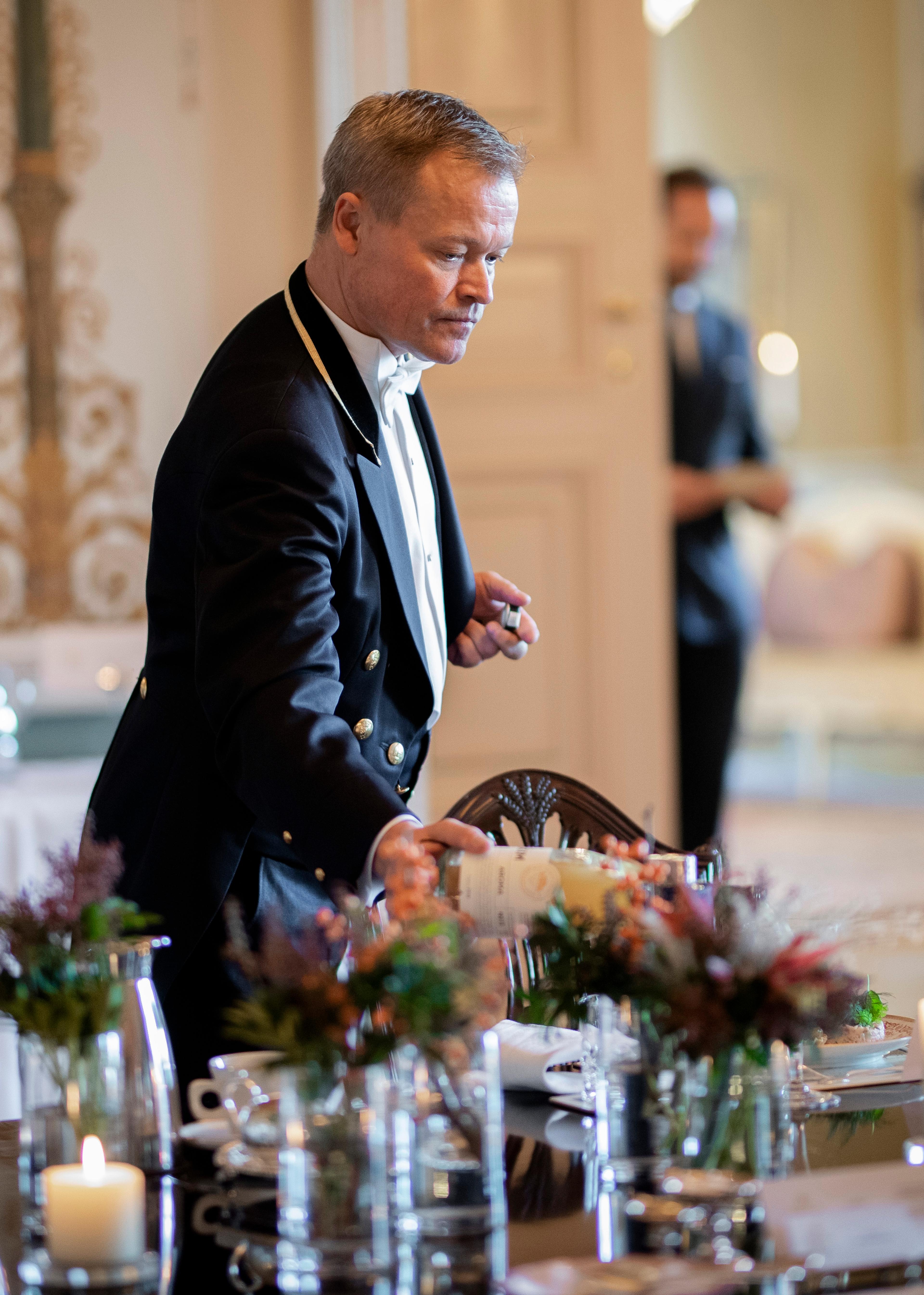 En livrékledd mann fyller glass med juice.