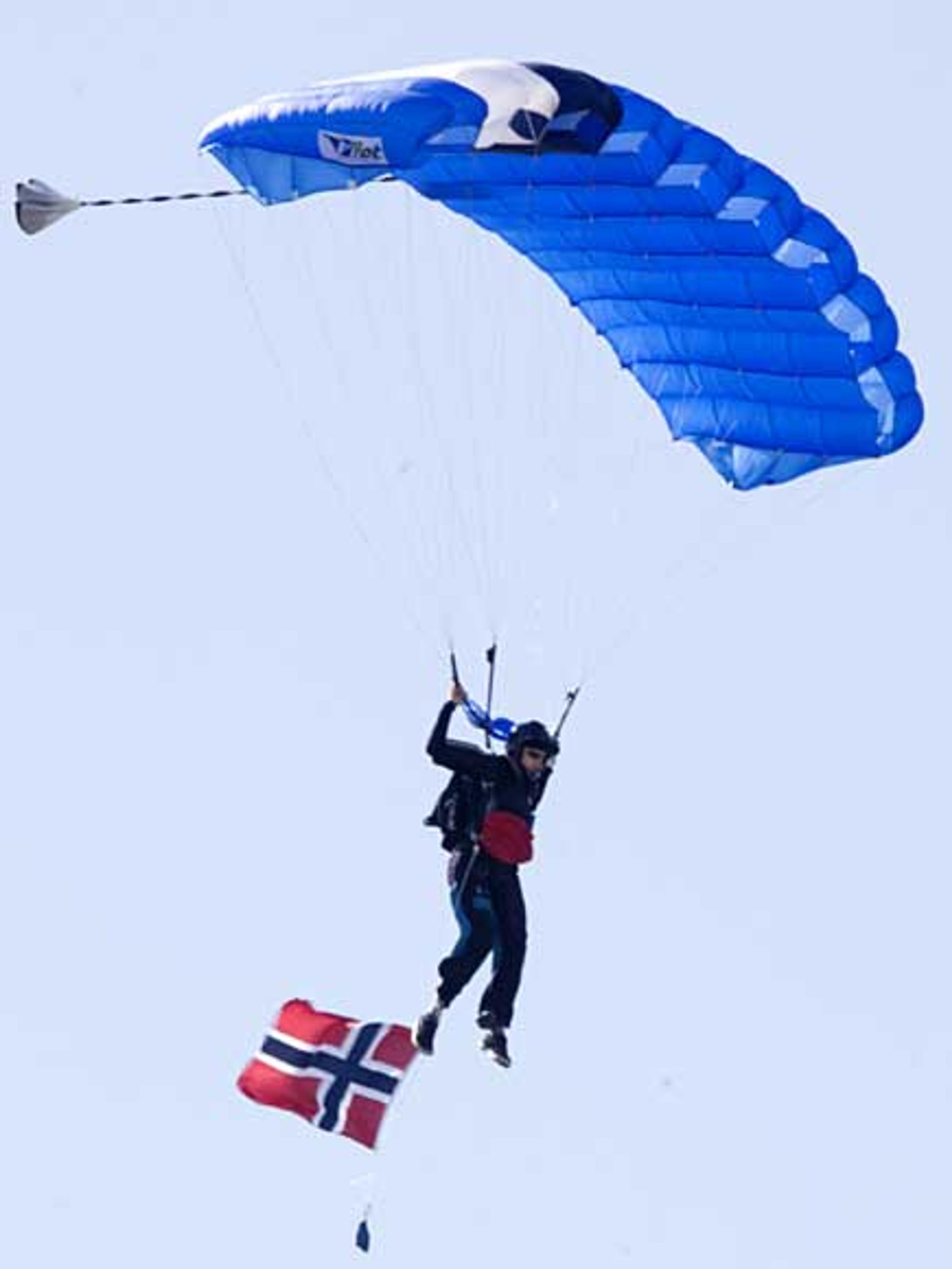 En hopper i svevet. Han har med et norsk flagg.