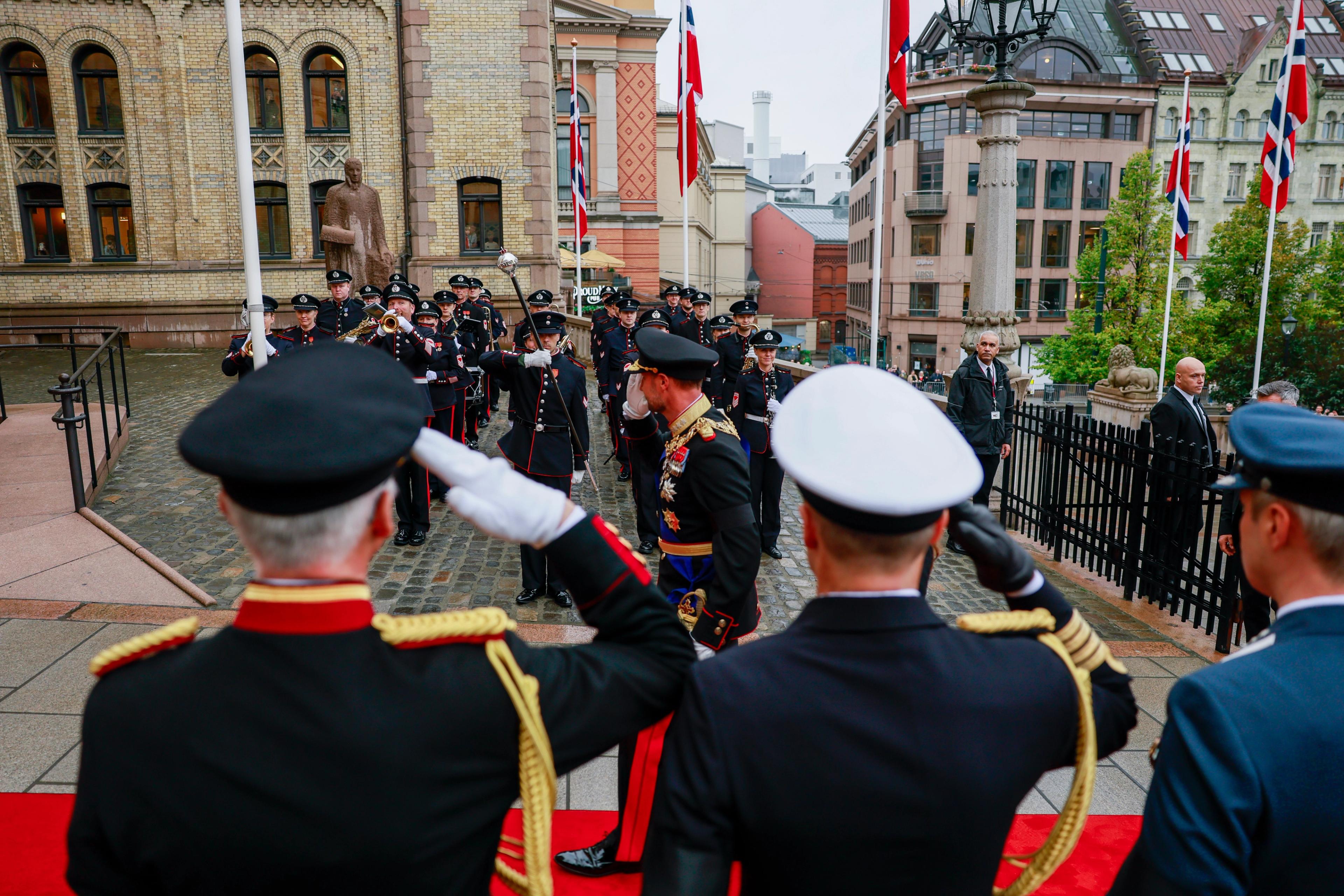 Kong Haakon hilser til Stabsmusikken utenfor stortingsbygningen.