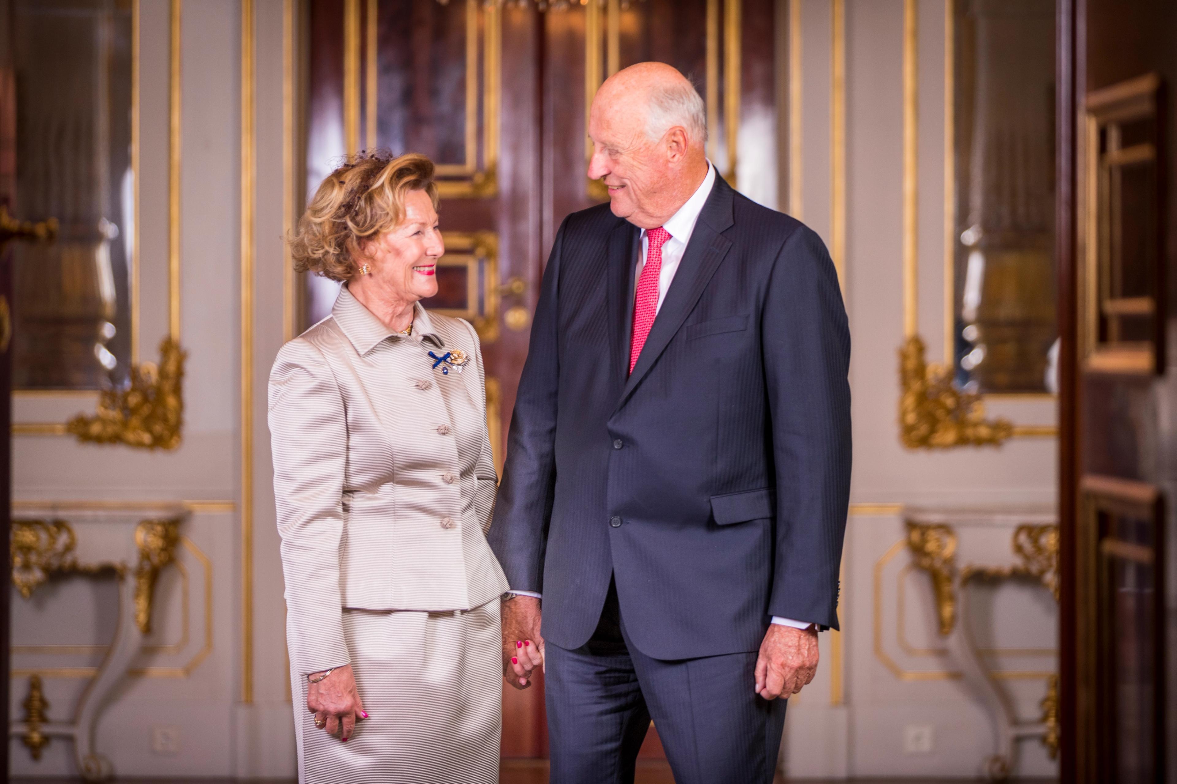 Kongen og Dronningen ser smilende på hverandre. Holder hverandre i hånden.