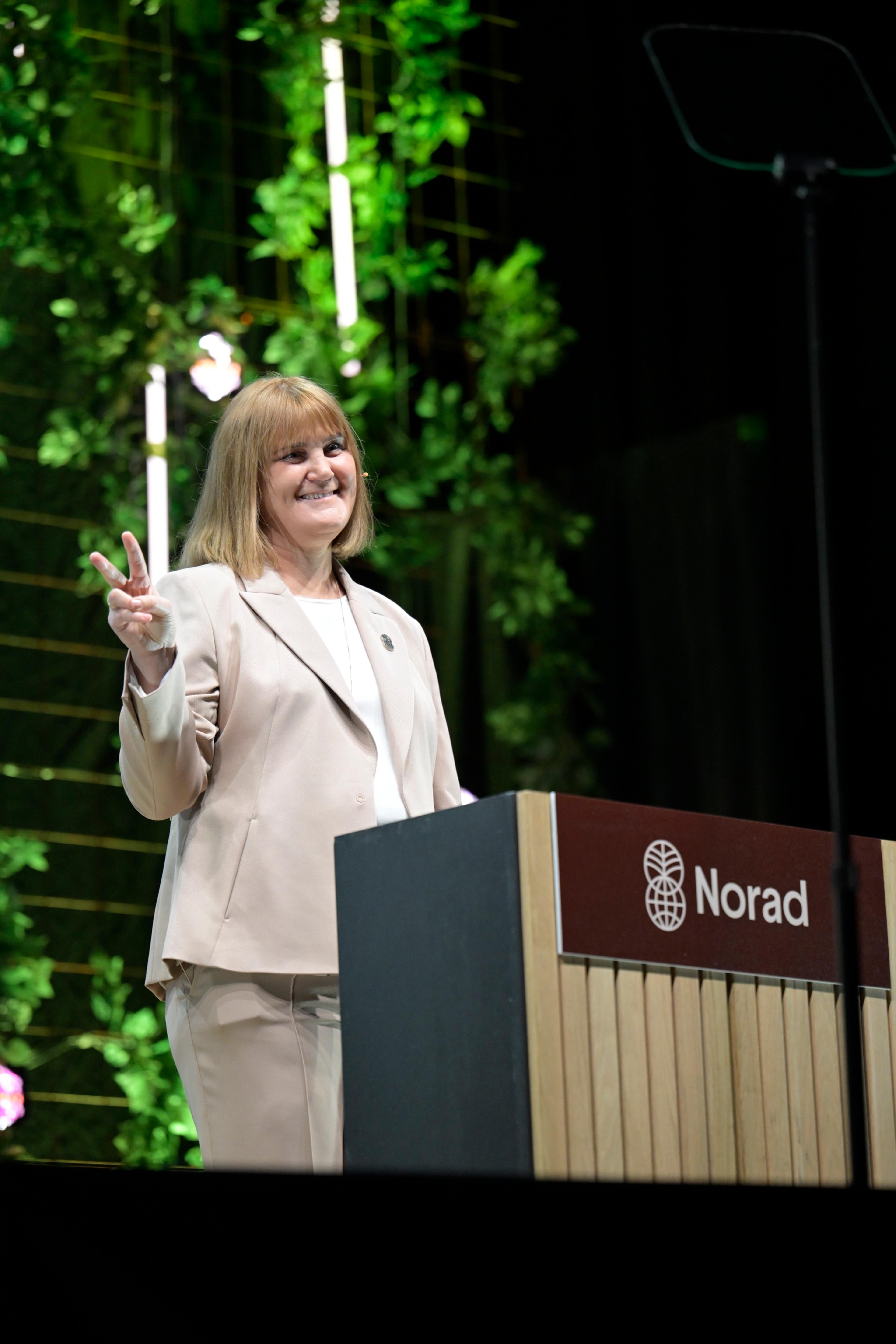 Gunn Jorid Roset smiler mens hun viser fredstegnet fra scenen.