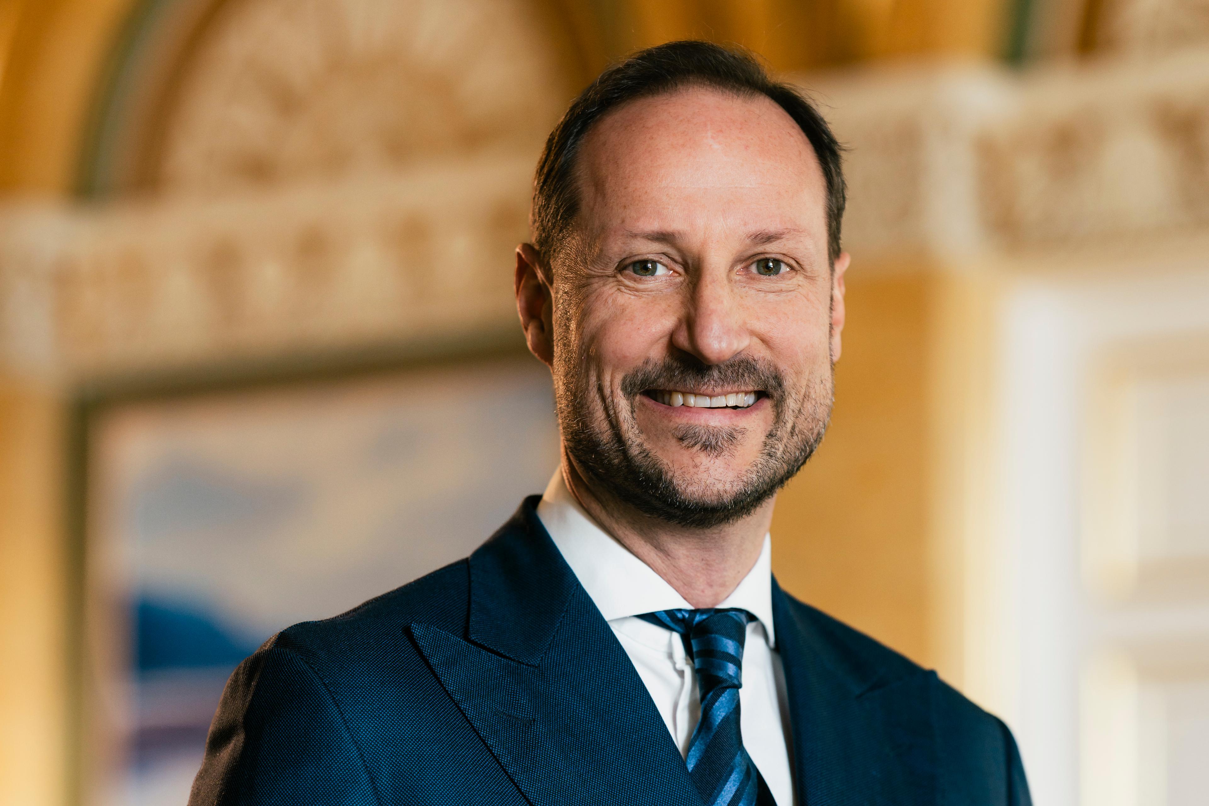 Portrett av Kronprins Haakon tatt i hvit skjorte mørkeblå dress med slips.