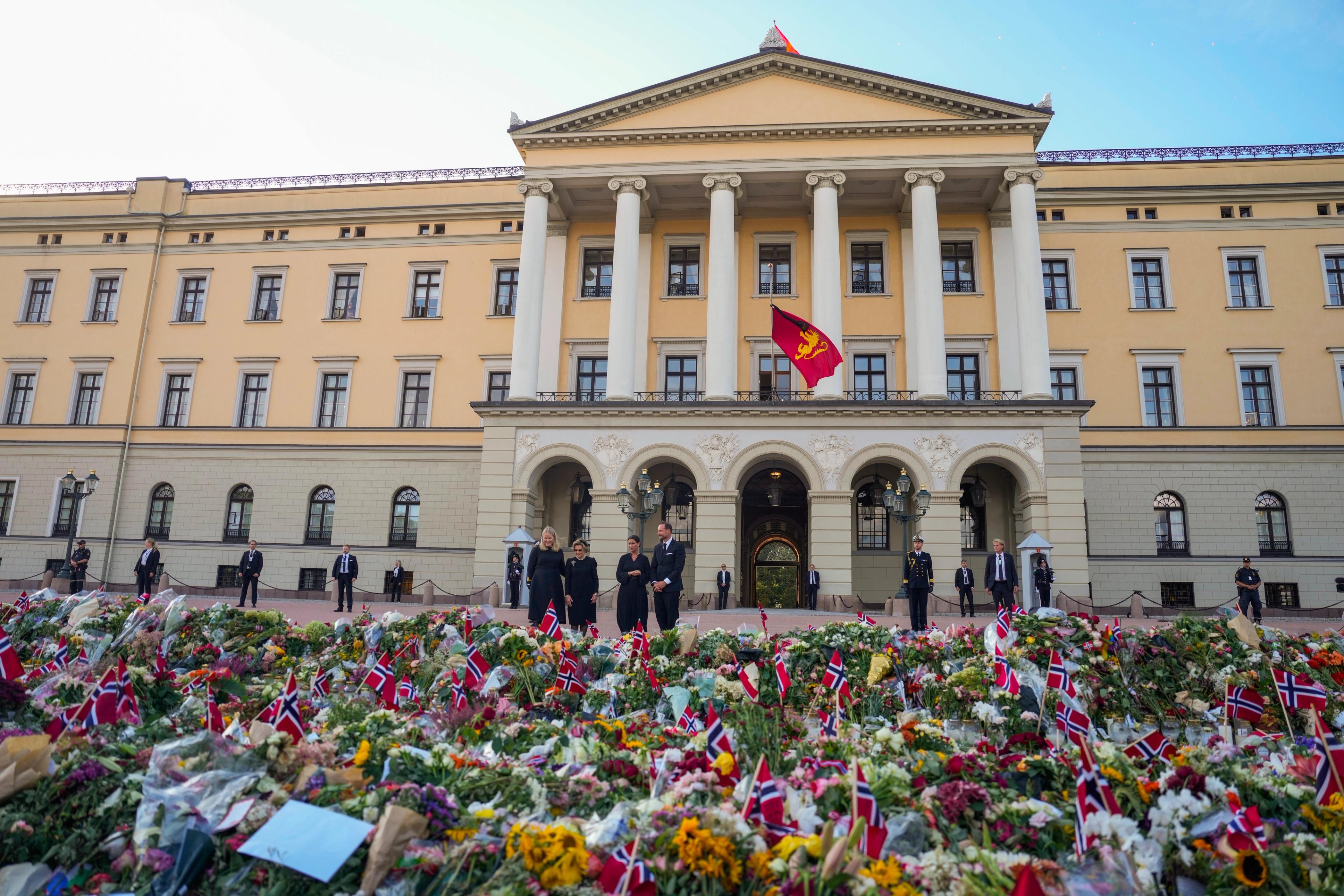 En enorm mengde blomster ligger på bakken foran Slottet, der kongeflagget vaier på halv stang fra Slottsbalkongen.
