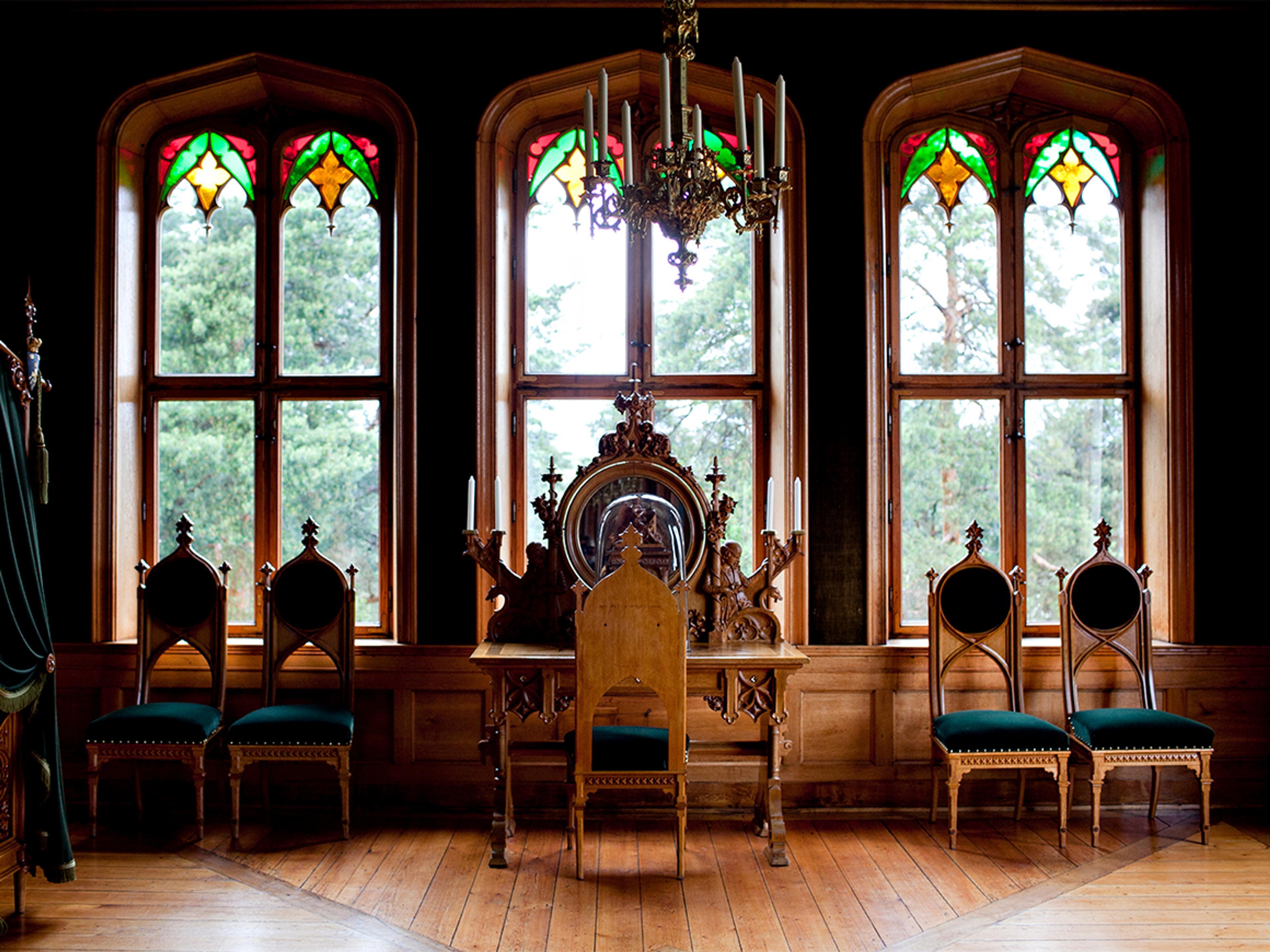 En skrivepult foran tre store vinduer.