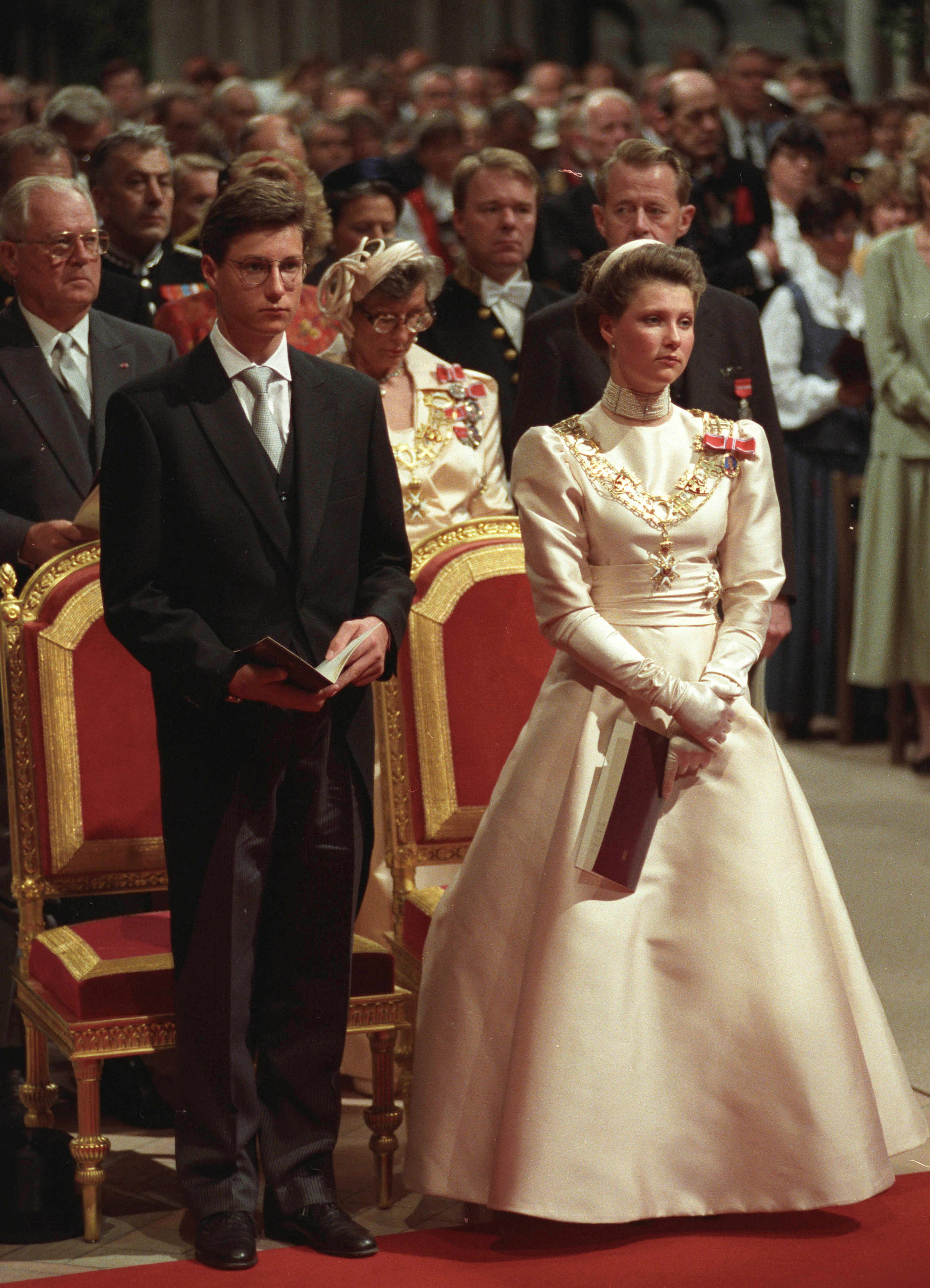 Kronprinsen og Prinsesse Märtha Louise står alvorlige og følger signingen.