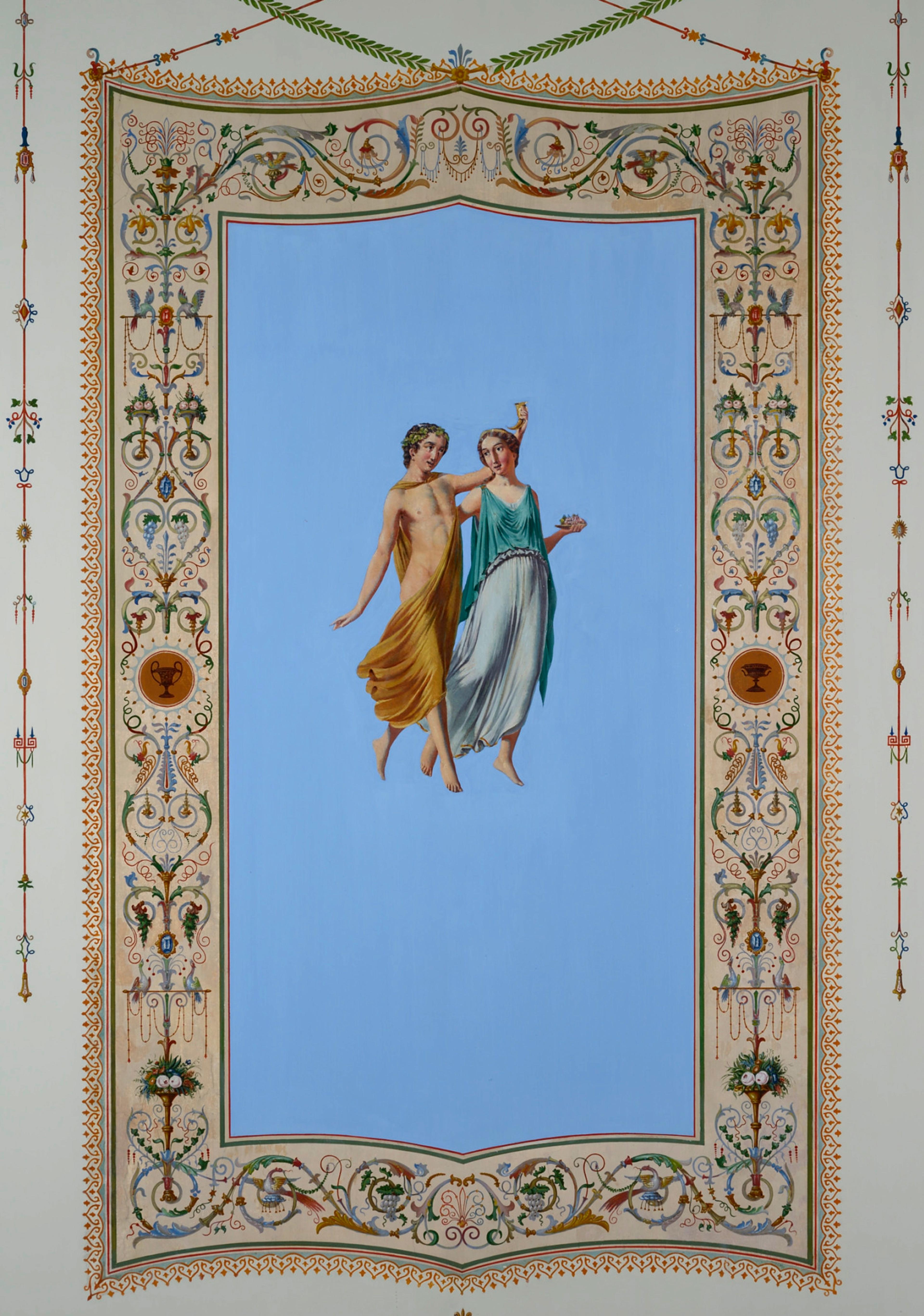 Et veggfelt med en mann og en kvinne i helfigur på lyseblå bakgrunn. De er kledd "klassisk gresk" - han er lettkledd og har vinløv i håret. Hun holder en matrett i den ene hånden, han løfter et drikkebeger. Feltet er innrammet av en fargerik, malt bord med mange detaljer.