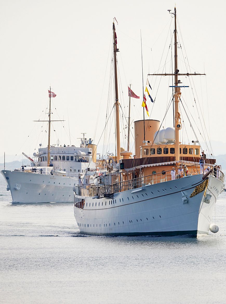 De to skipene går inn mot kai. Det norske kongeskipet først, etterfulgt av Dannebrog.