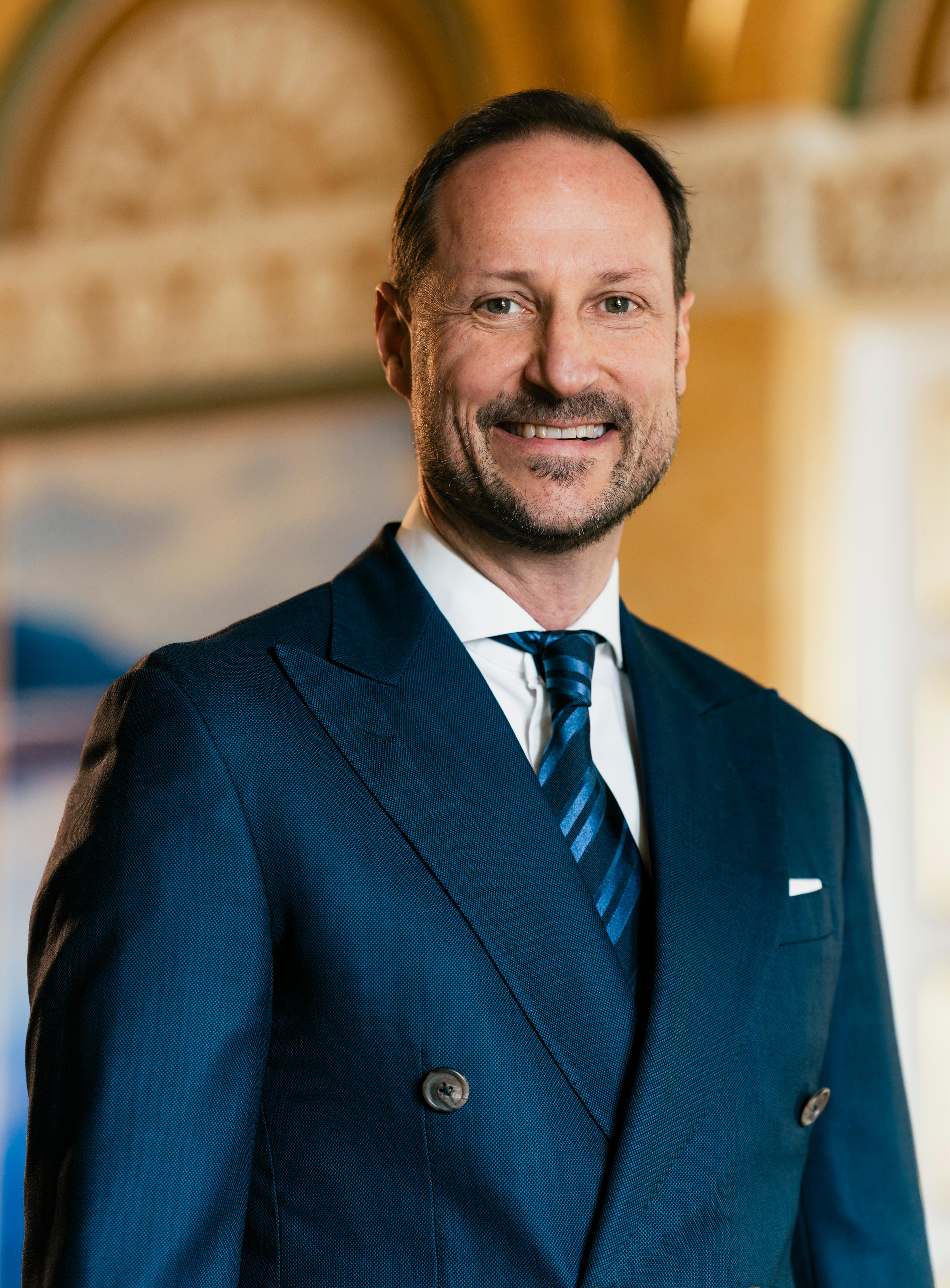 Portrett av Kronprins Haakon tatt i hvit skjorte mørkeblå dress med slips.