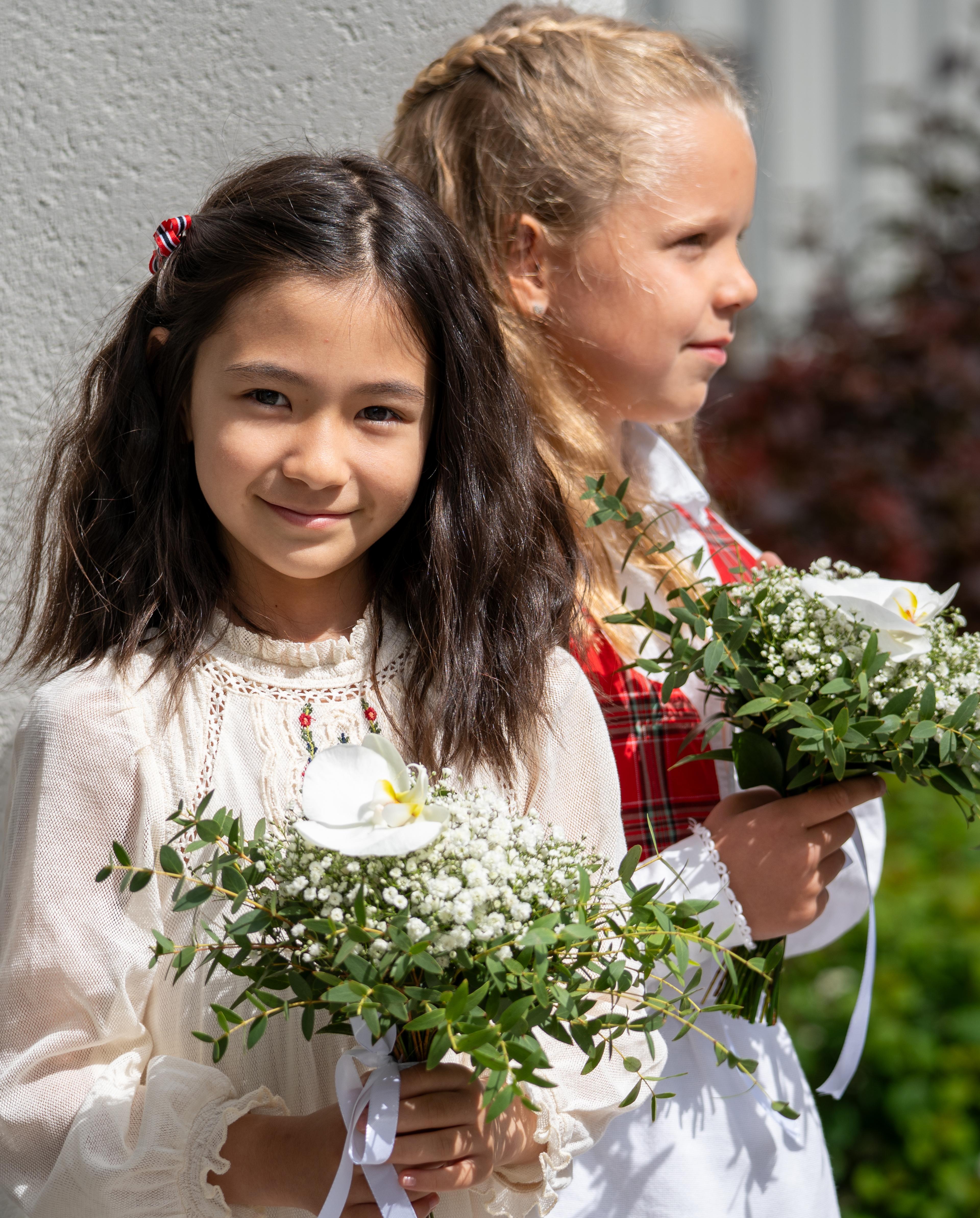 Jenny ser rett i kamera mens hun holder i blomsterbukett i hendene.