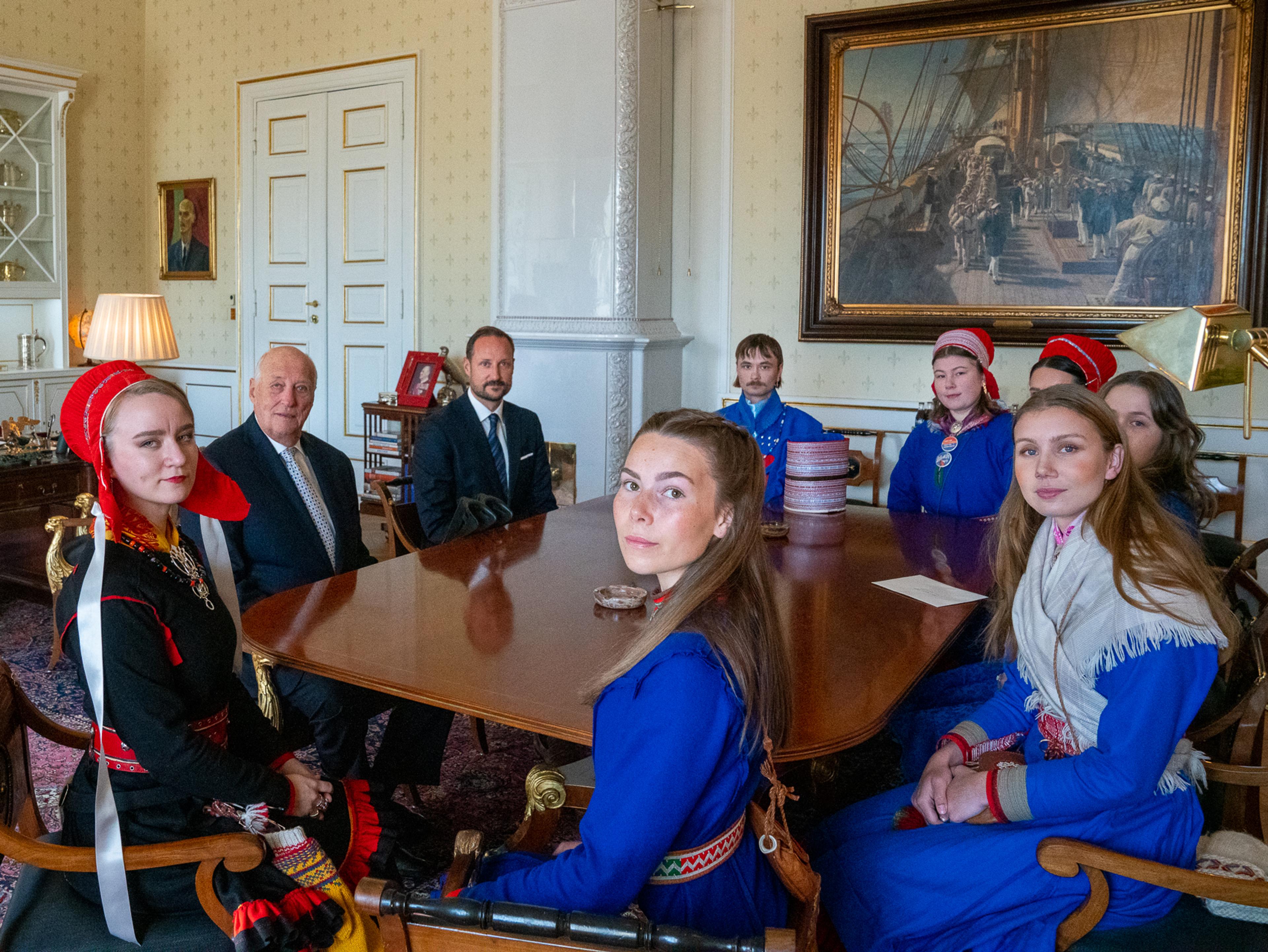 Representanter for Fosen-aksjonistene sitter med Kong Harald og Kronprins Haakon rundt møtebordet på Kongens kontor. Alle aksjonistene er kledd i samekofter.