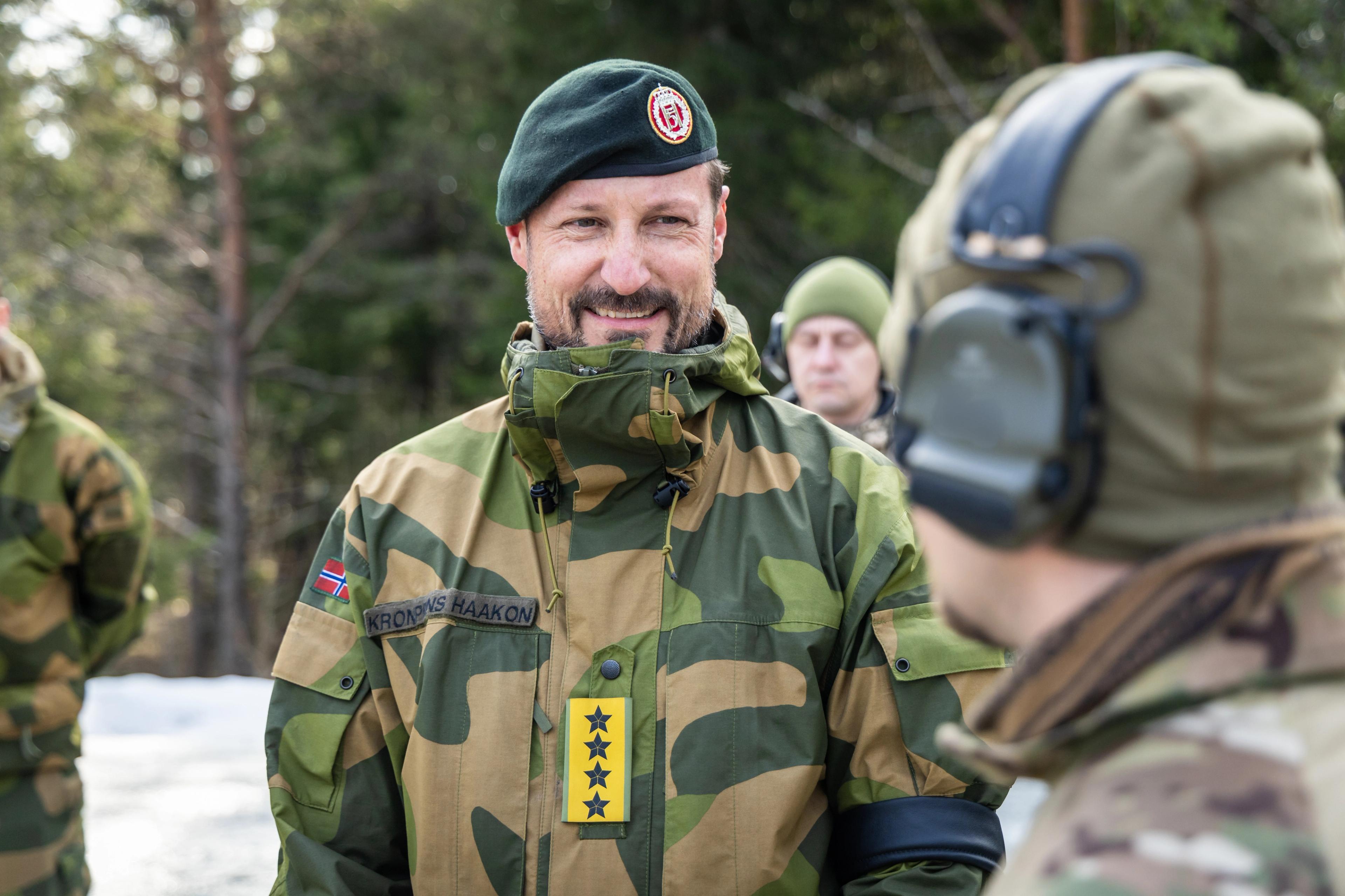 Kronprins Haakon ser på en soldat vi ikke ser ansiktet på.