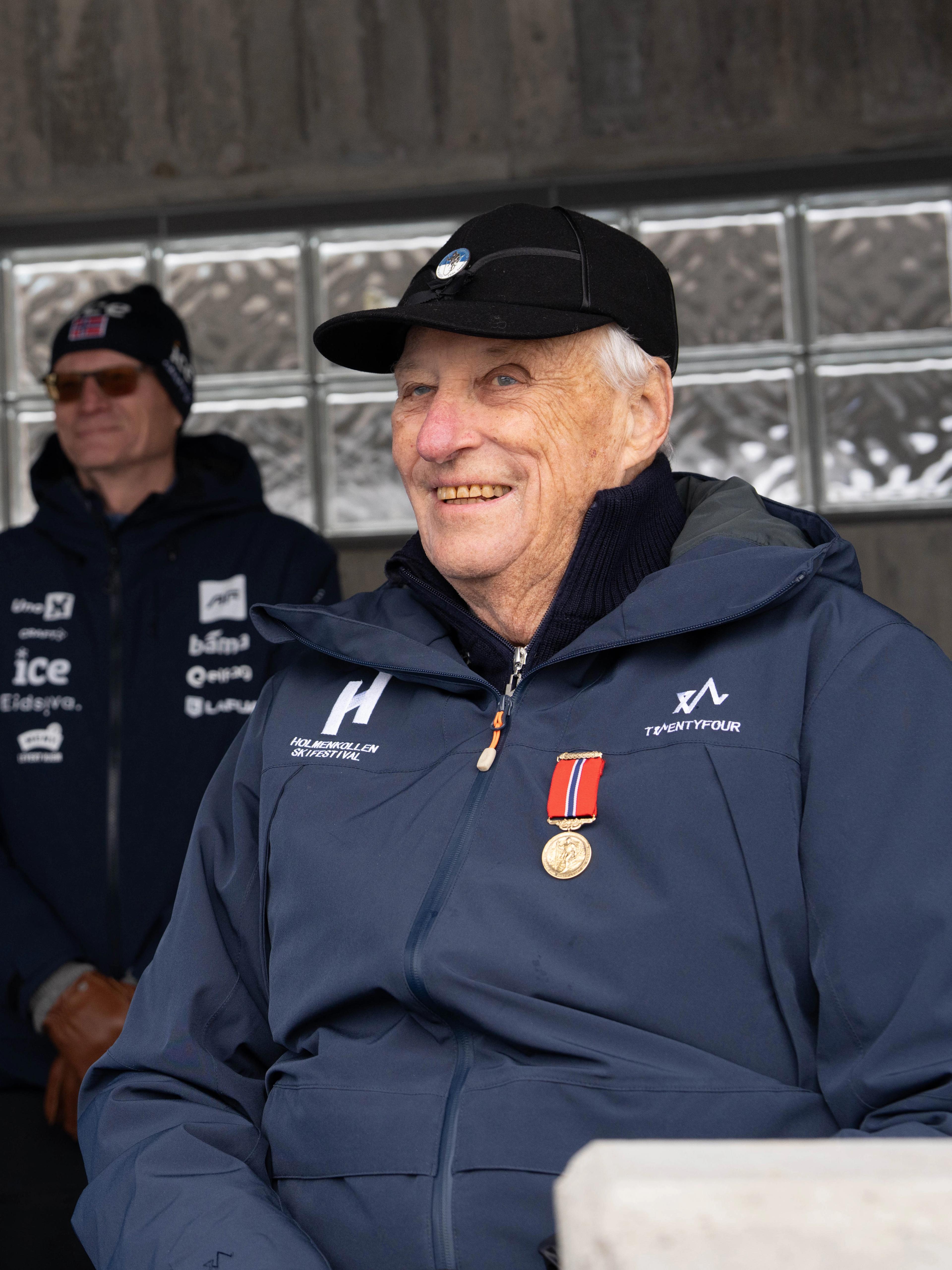 Tett på Kong Harald iført caps frå Skiforeningen og med Holmenkollmedaljen festa på jakka.