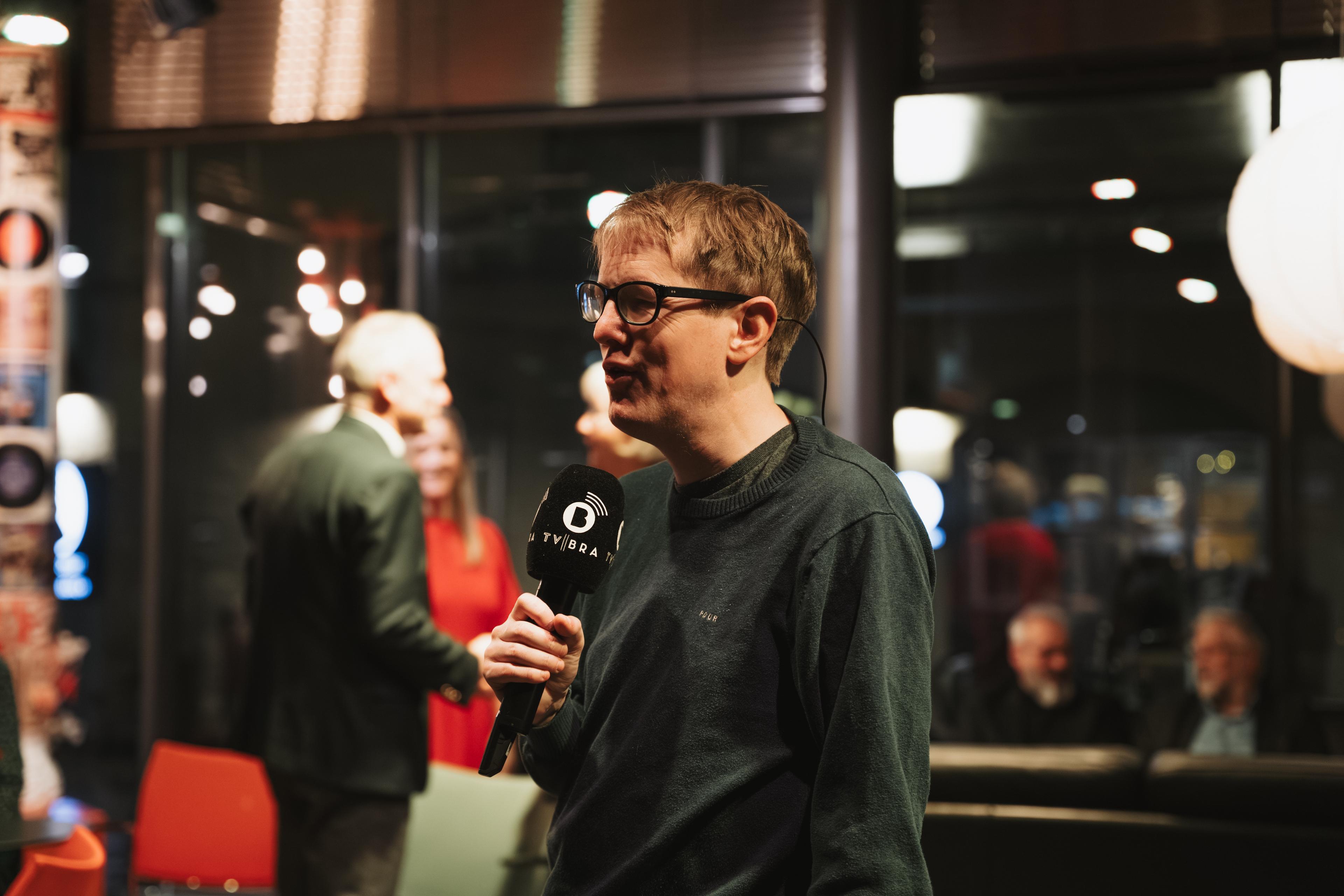 Reporter frå TV BRA snakkar inn i mikrofonen i foajeen.