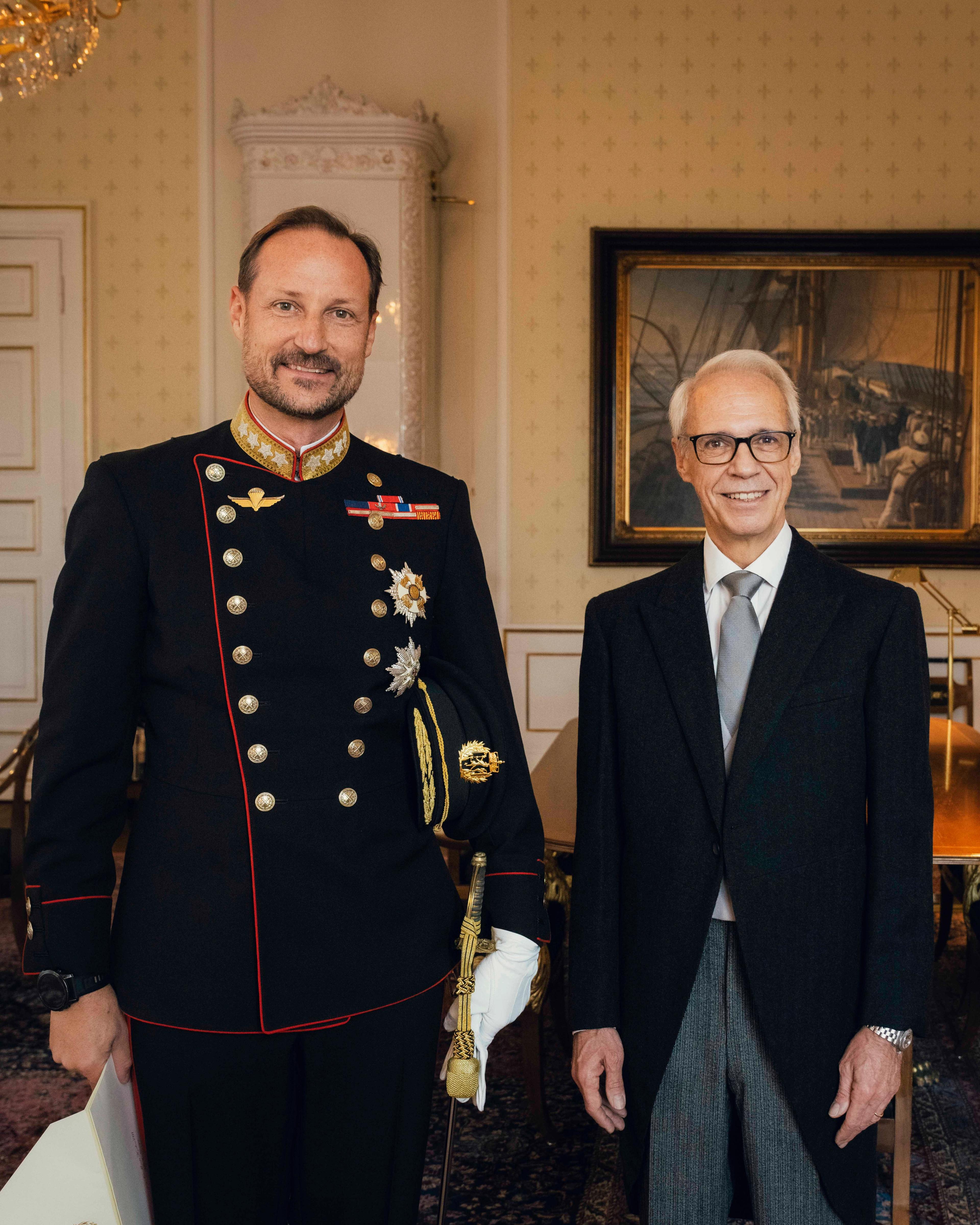 Kongen i gallauniform og ambassadøren i sjakett, står smilende ved siden av hverandre på Kongens kontor.
