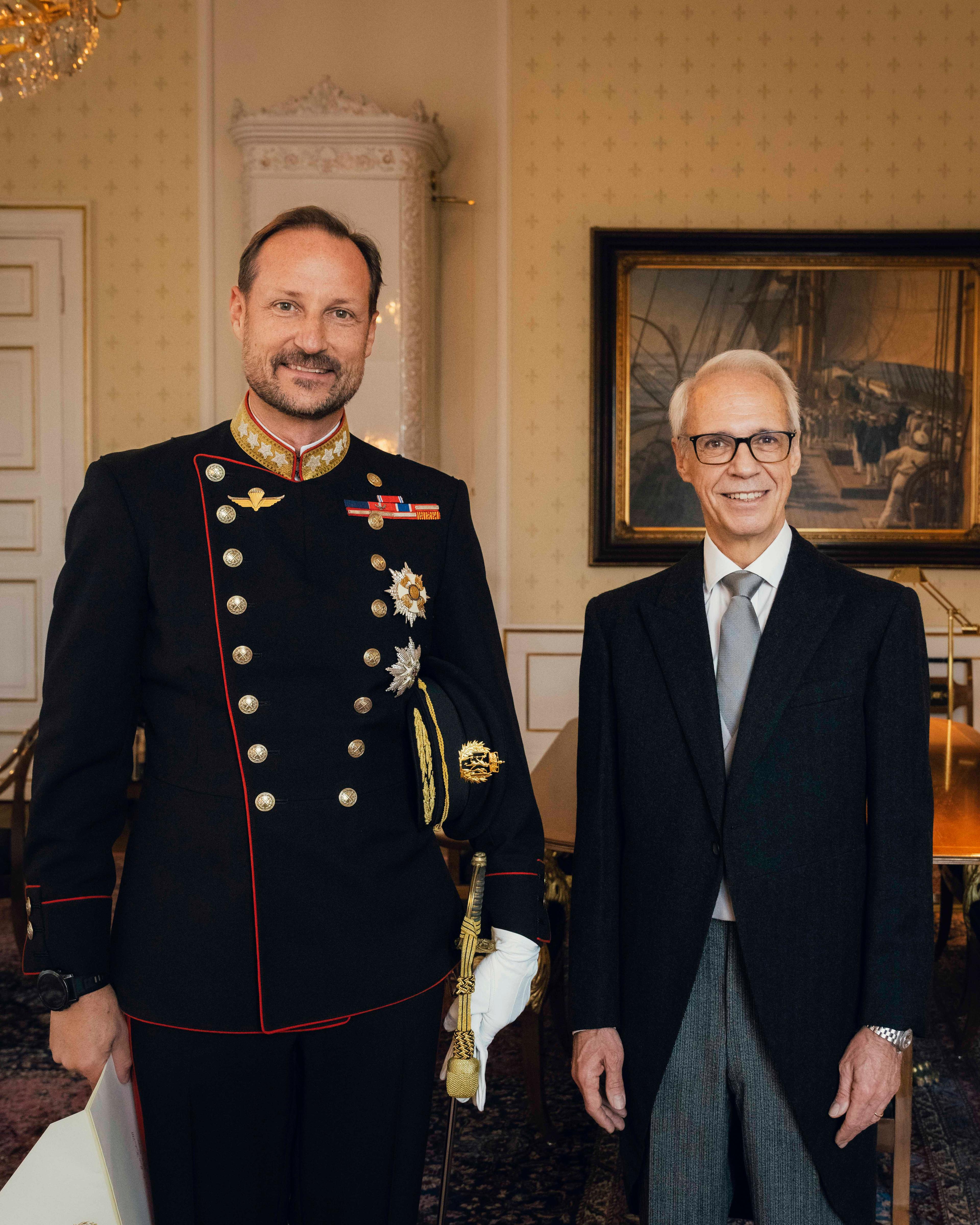 Kongen i gallauniform og ambassadøren i sjakett, står smilende ved siden av hverandre på Kongens kontor.