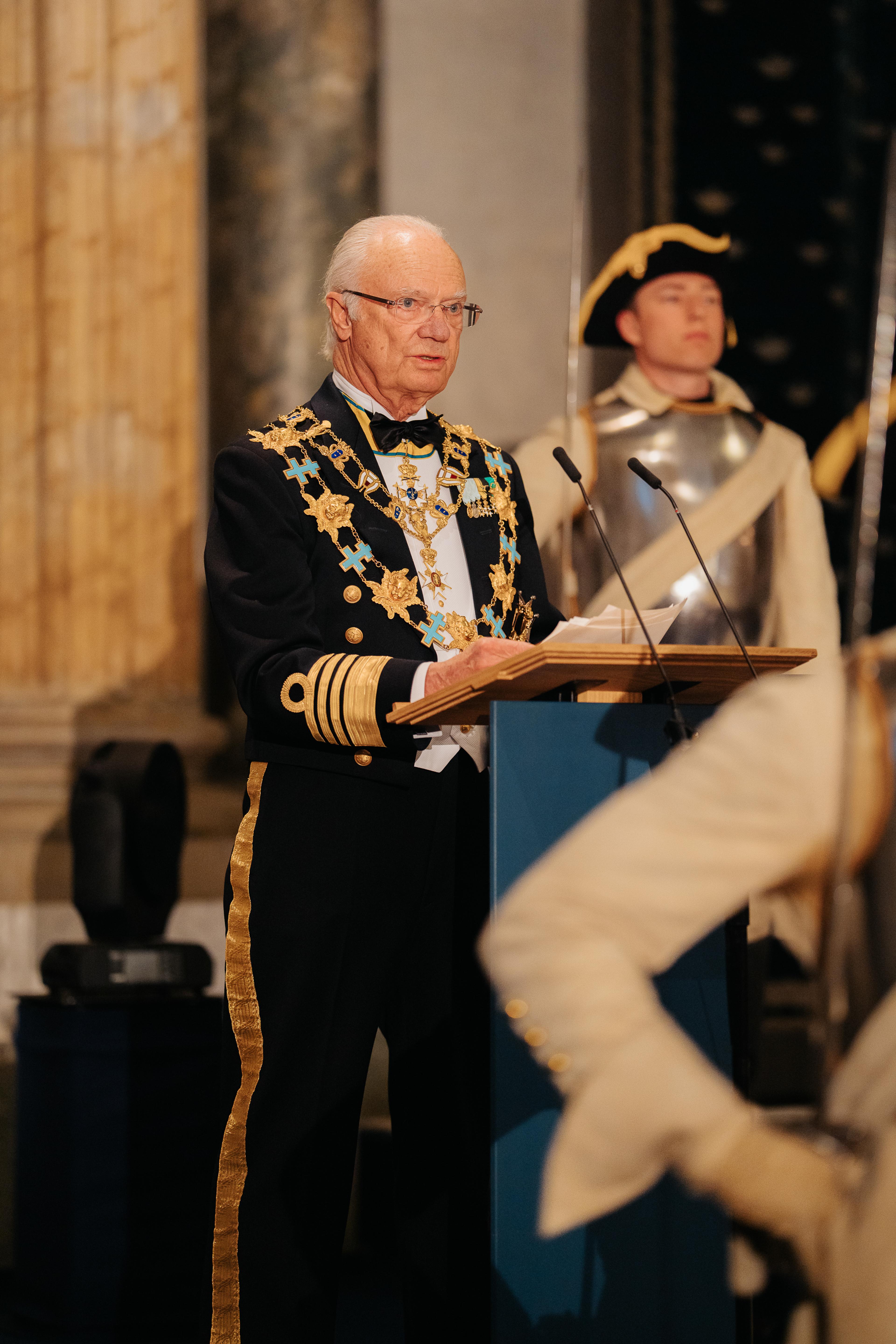 Kong Carl Gustaf på talerstolen i marinens gallauniform med ordenskjeder.